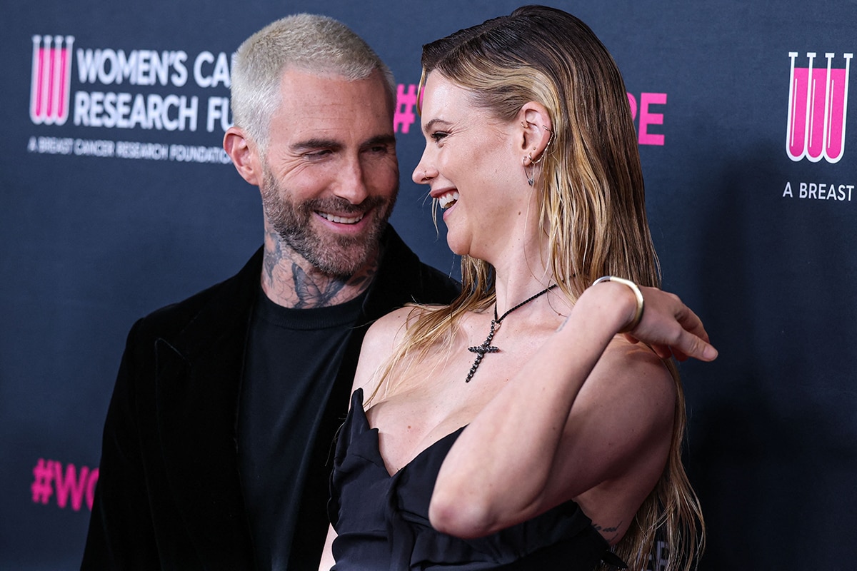 Adam Levine and Behati Prinsloo share a sweet moment on the red carpet, with Behati showcasing her cross pendant necklace and strapless Vivienne Westwood minidress