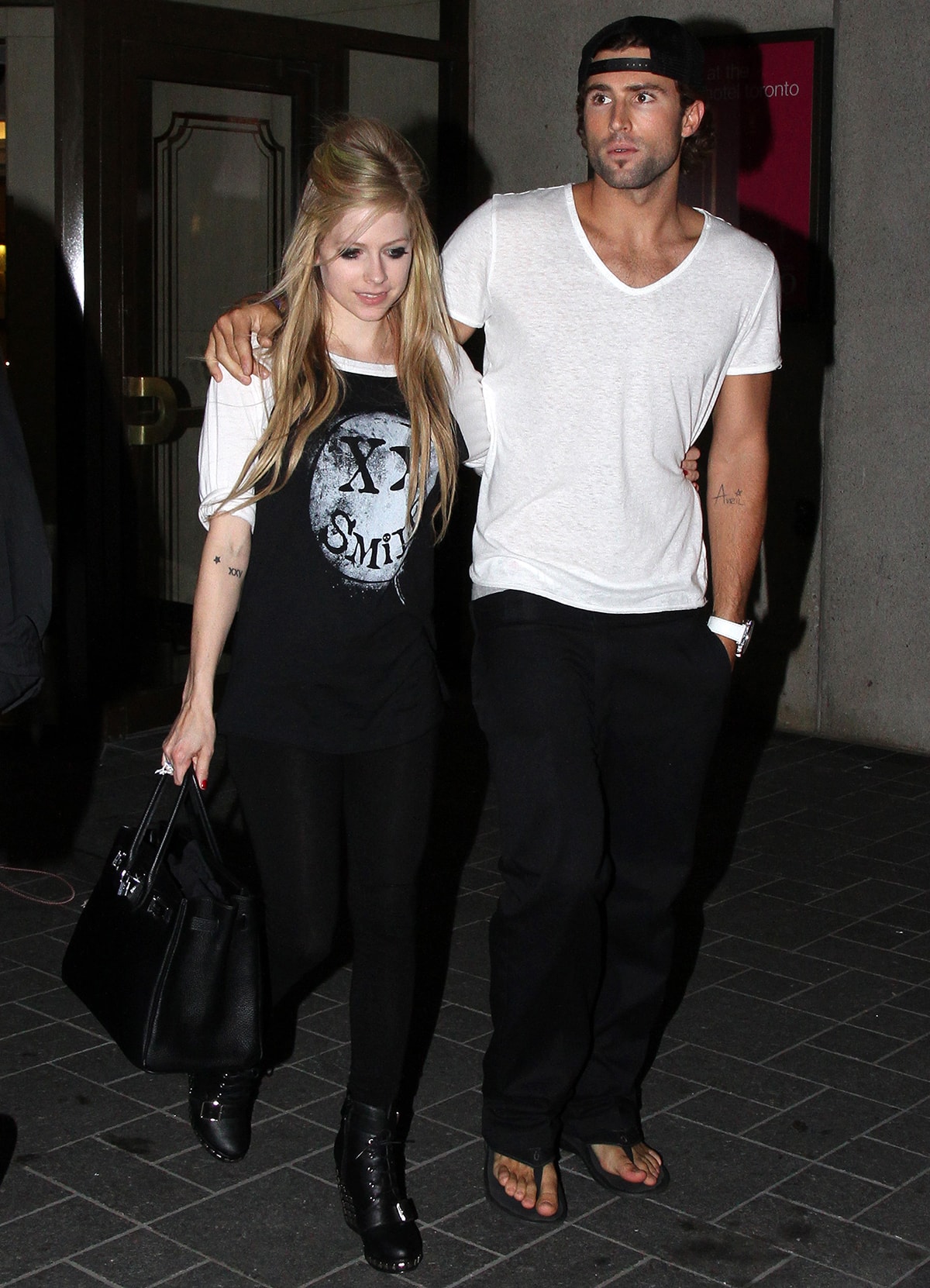 Avril Lavigne steps out with then-boyfriend Brody Jenner in 2011, wearing black leggings, a graphic tee, and studded ankle boots that added her signature punk edge to an otherwise relaxed, monochrome outfit