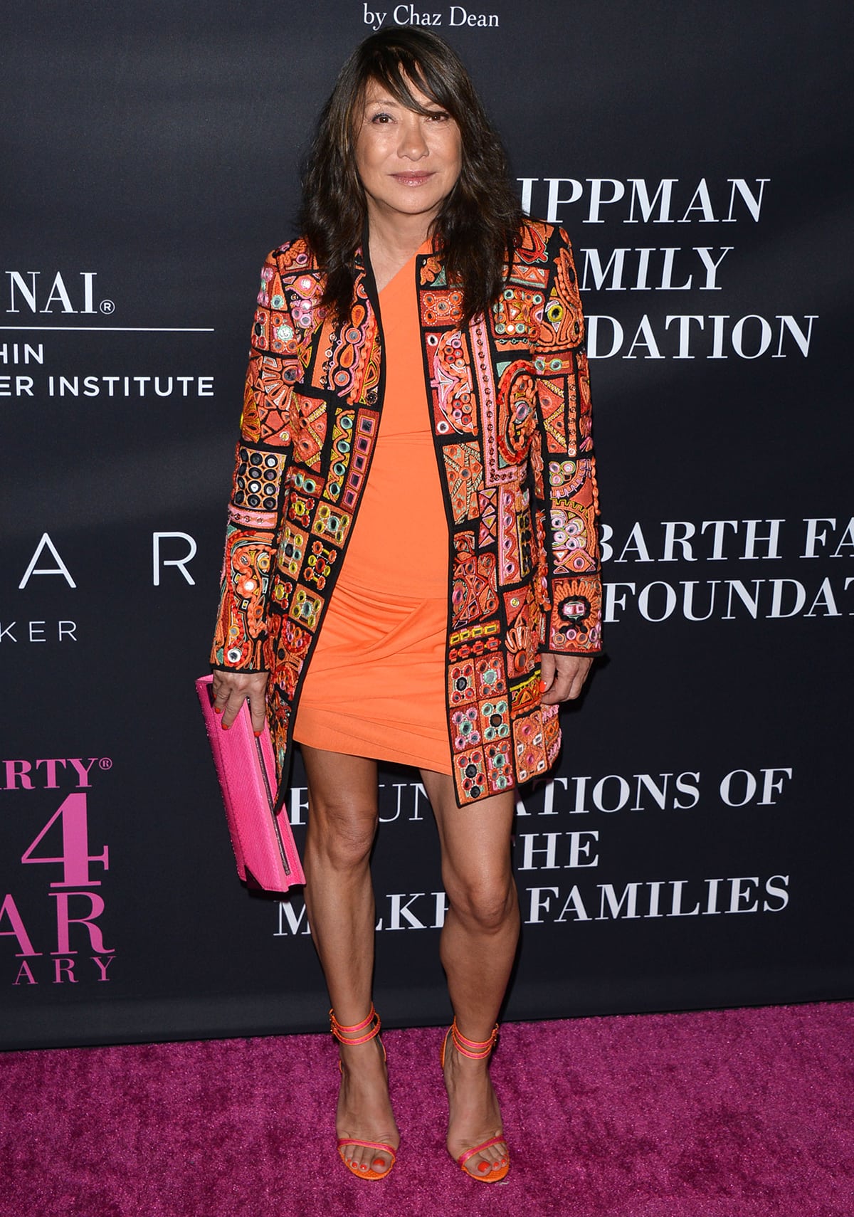 Barbara Bui pairs strappy orange heels with a vivid patchwork jacket and matching mini dress, reinforcing her signature bold, rock-chic aesthetic