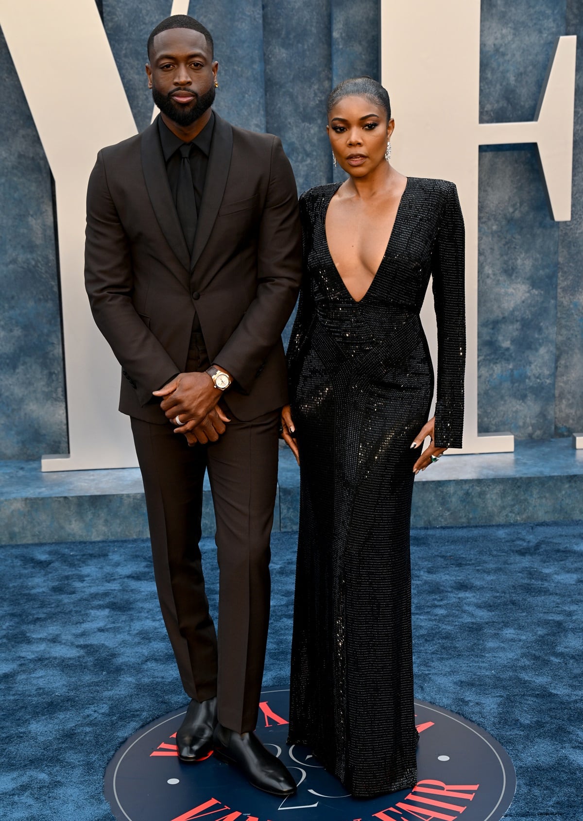 Gabrielle Union shimmered in a plunging, floor-length Ralph Lauren gown that skimmed the carpet and concealed her likely platform heels, while Dwyane Wade complemented her sleek monochrome moment in a tailored Prada suit finished with polished black leather dress shoes at the 2023 Vanity Fair Oscar Party held at the Wallis Annenberg Center for the Performing Arts on March 12, 2023, in Beverly Hills, California