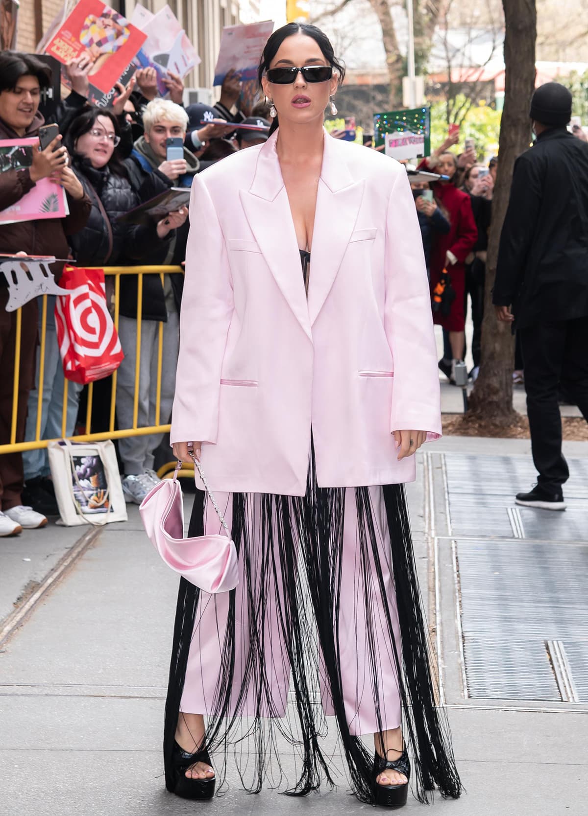 Katy Perry layers a black fringe dress beneath a boxy pink Alexander Wang two-piece suit, finishing the bold statement look with snakeskin-embossed open-toe platform pumps that elevate her 5’7″ (170.2 cm) frame and showcase her matching pink pedicure