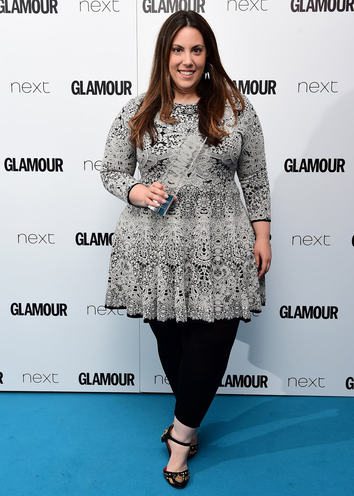 Mary Katrantzou stuns in an intricately patterned dress paired with embellished black heels, holding her well-deserved Glamour award with a radiant smile