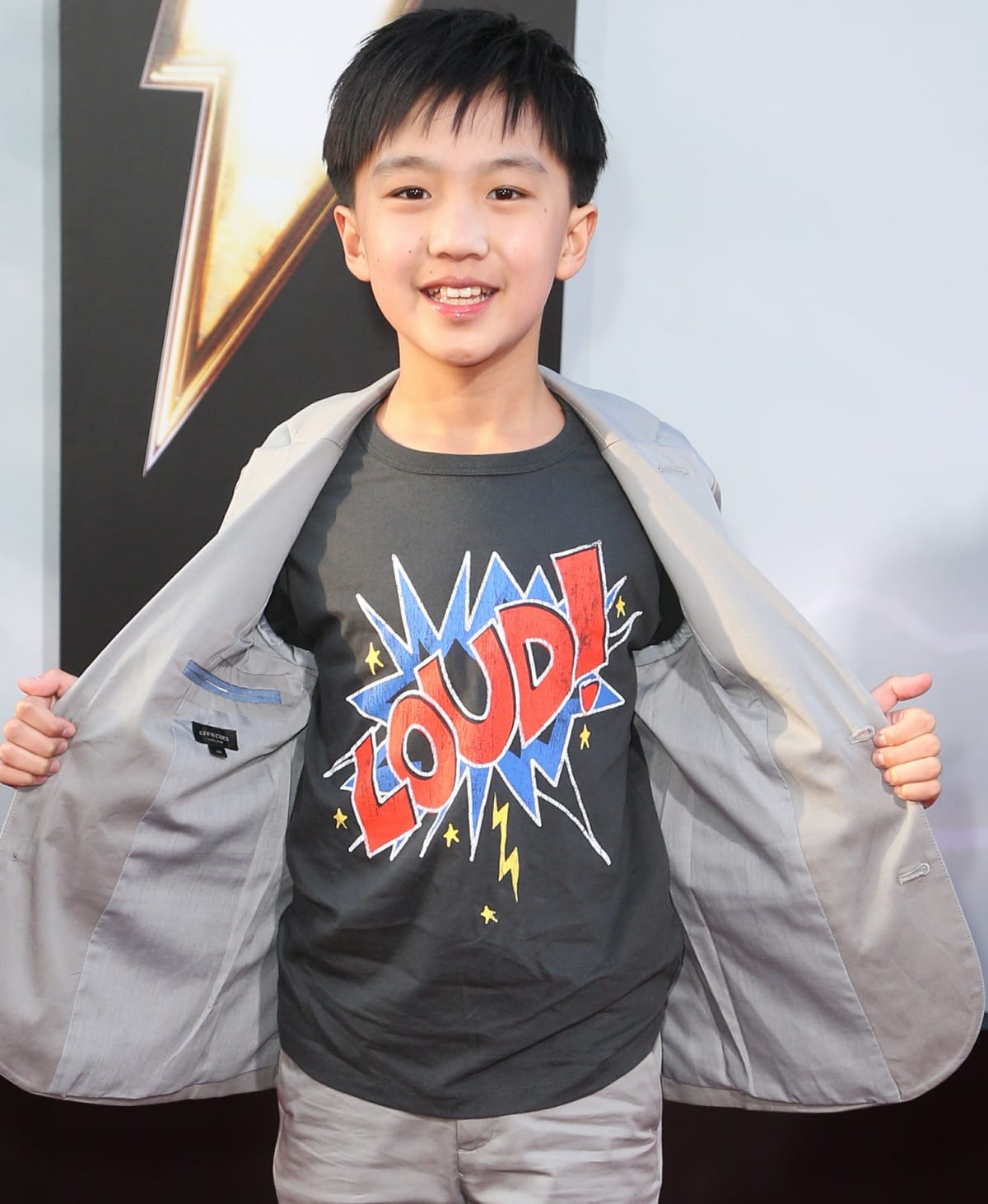 Ian Chen playfully shows off his "Loud!" graphic tee at the premiere of Shazam! Fury of the Gods
