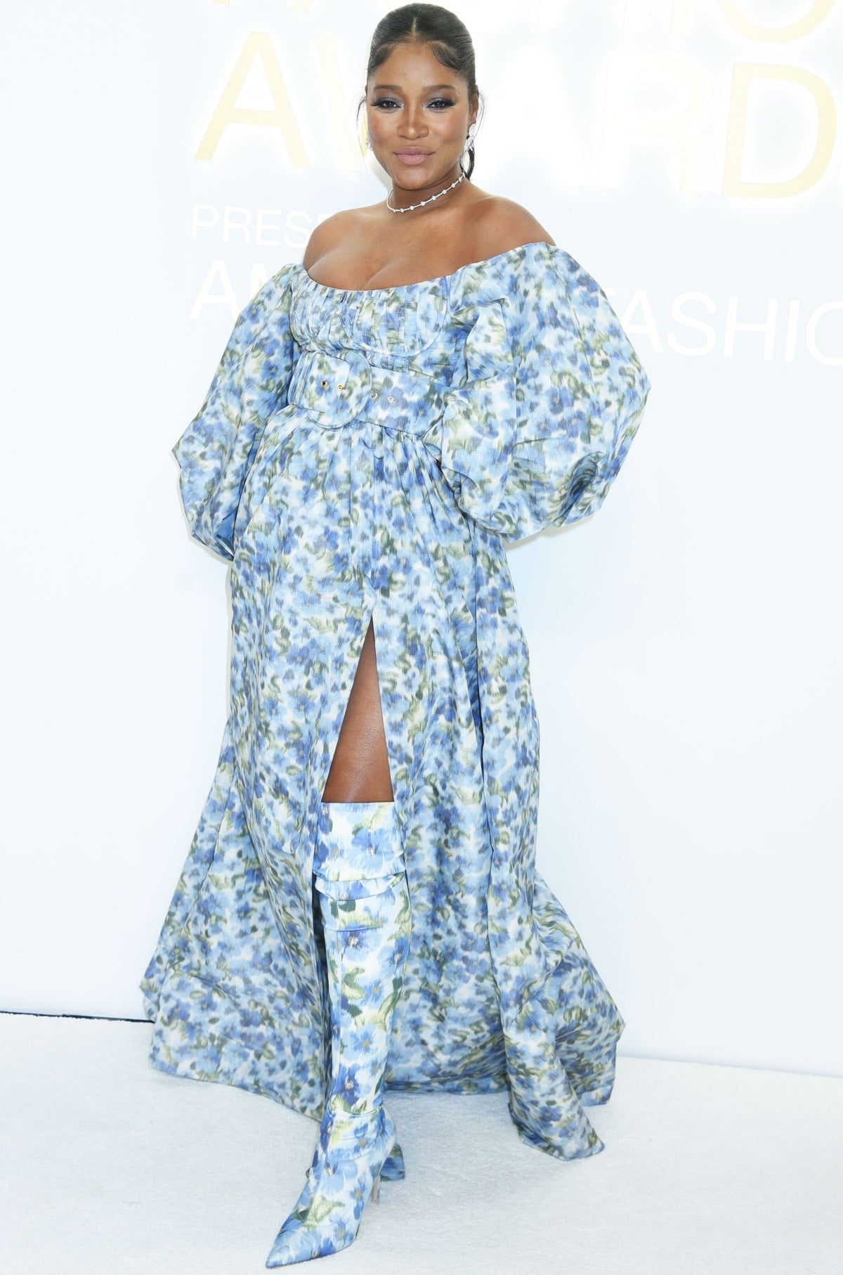Floral knee-high boots in a matching print elevate the off-the-shoulder gown, while a delicate choker necklace adds a polished, romantic finish