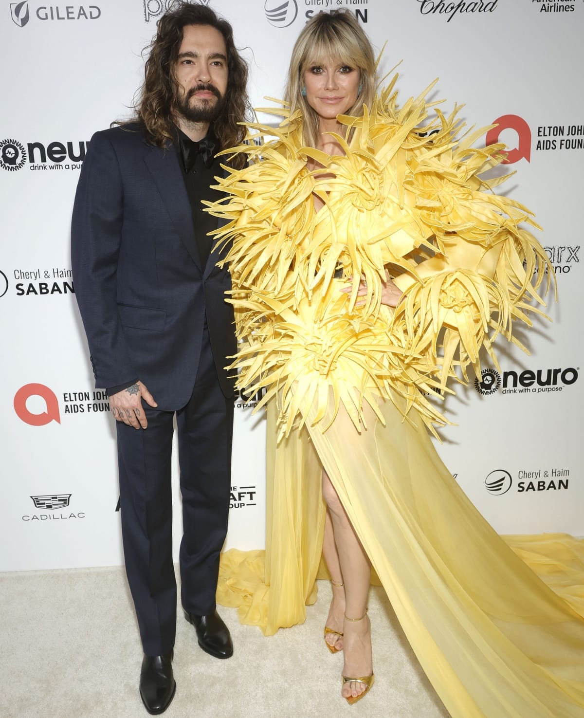 Tom Kaulitz joined Heidi Klum on the red carpet as she stepped out in a sculptural yellow Georges Hobeika gown, grounded by minimalist gold ankle-strap Giuseppe Zanotti heels that elongated the leg and balanced the look’s dramatic feathered volume