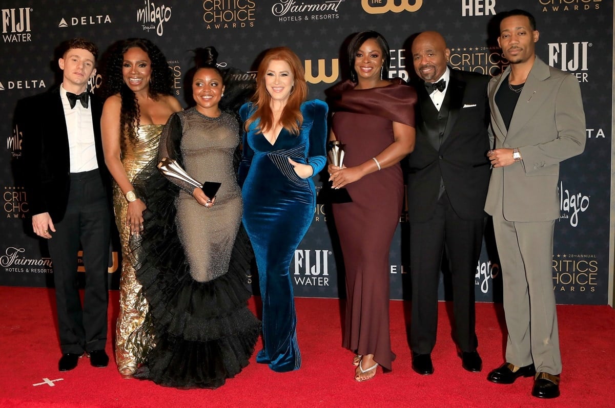 (L–R) Chris Perfetti, Sheryl Lee Ralph in metallic gold, Quinta Brunson in a sheer ruffled gown, Lisa Ann Walter in velvet blue, Janelle James in burgundy with strappy heels, William Stanford Davis, and Tyler James Williams in two-tone loafers celebrate Abbott Elementary's Best Comedy Series win at the 2023 Critics Choice Awards held January 15 at the Fairmont Century Plaza in Los Angeles