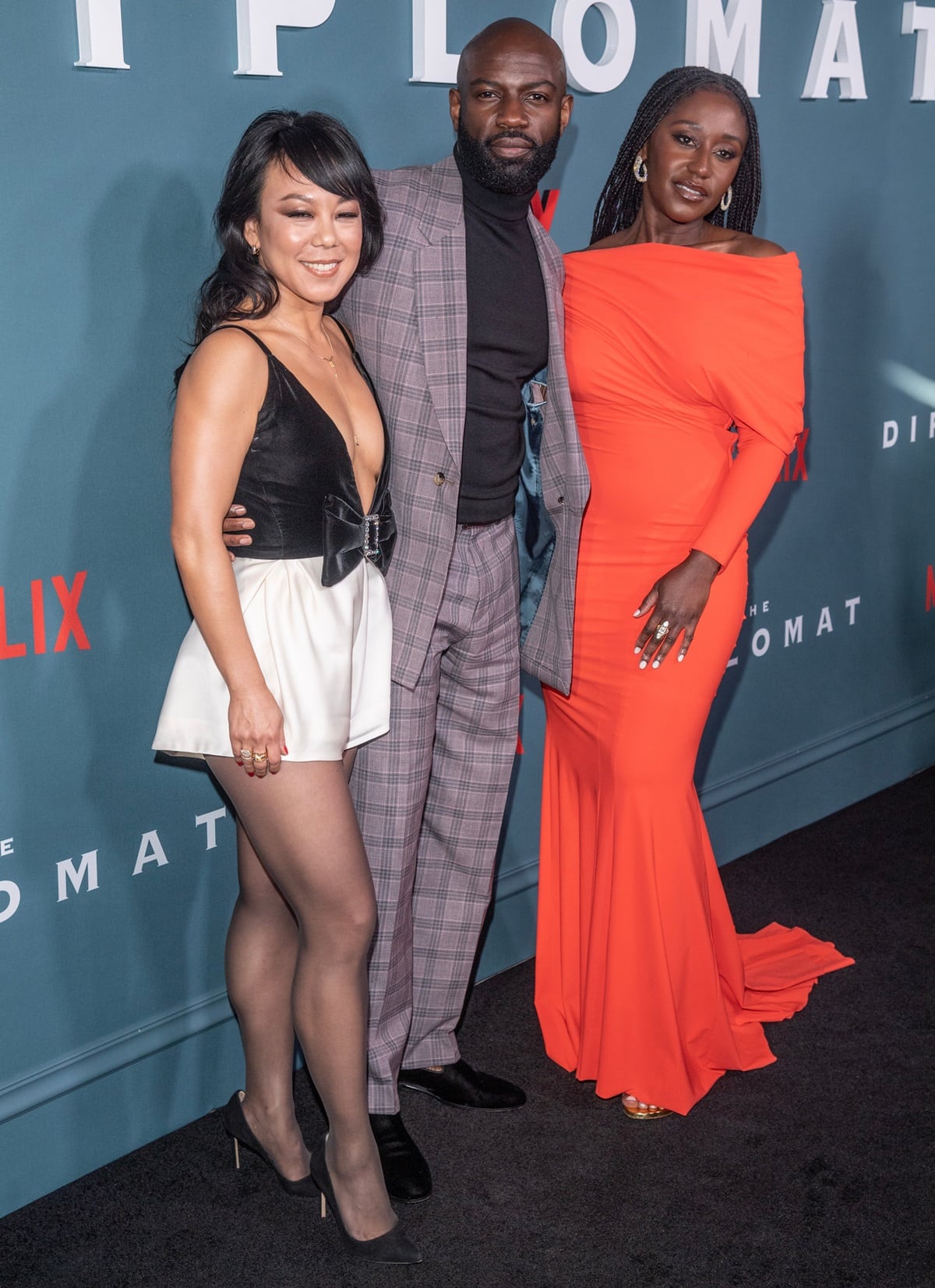 Posing with co-stars Ali Ahn and Nana Mensah, David Gyasi exuded effortless cool in a lavender plaid suit and black turtleneck, paired with sleek black dress shoes, while Ali stunned in a plunging black-and-white mini with pointed stilettos and Nana turned heads in a bold off-the-shoulder orange gown with gold heels