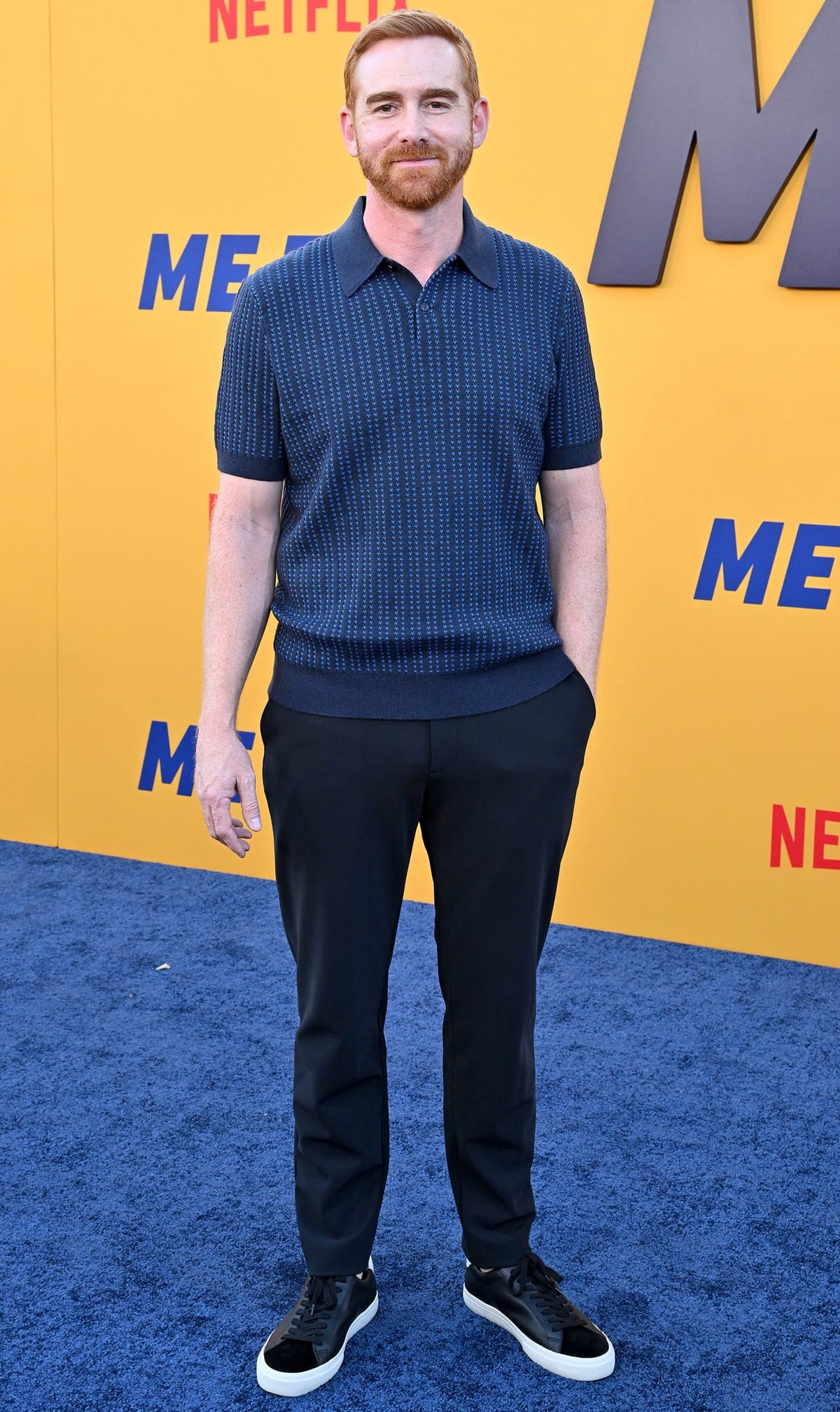 Andrew Santino kept it casually polished in a textured navy knit polo, tapered trousers, and black velvet low-top sneakers with white soles