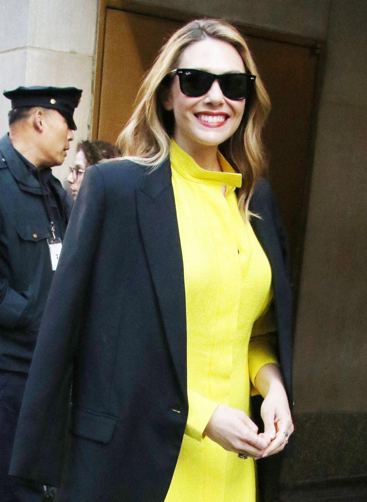 Elizabeth Olsen exudes effortless confidence in a structured yellow Proenza Schouler dress topped with a draped black blazer and signature red lipstick as she greets fans outside the Today show