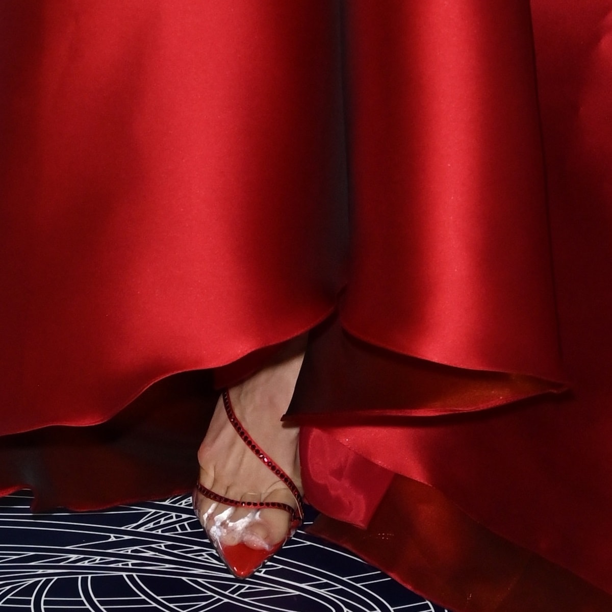 A close-up of Katharine McPhee's scarlet pointed-toe heels with crystal-lined straps, peeking out from under her Gemy Maalouf gown