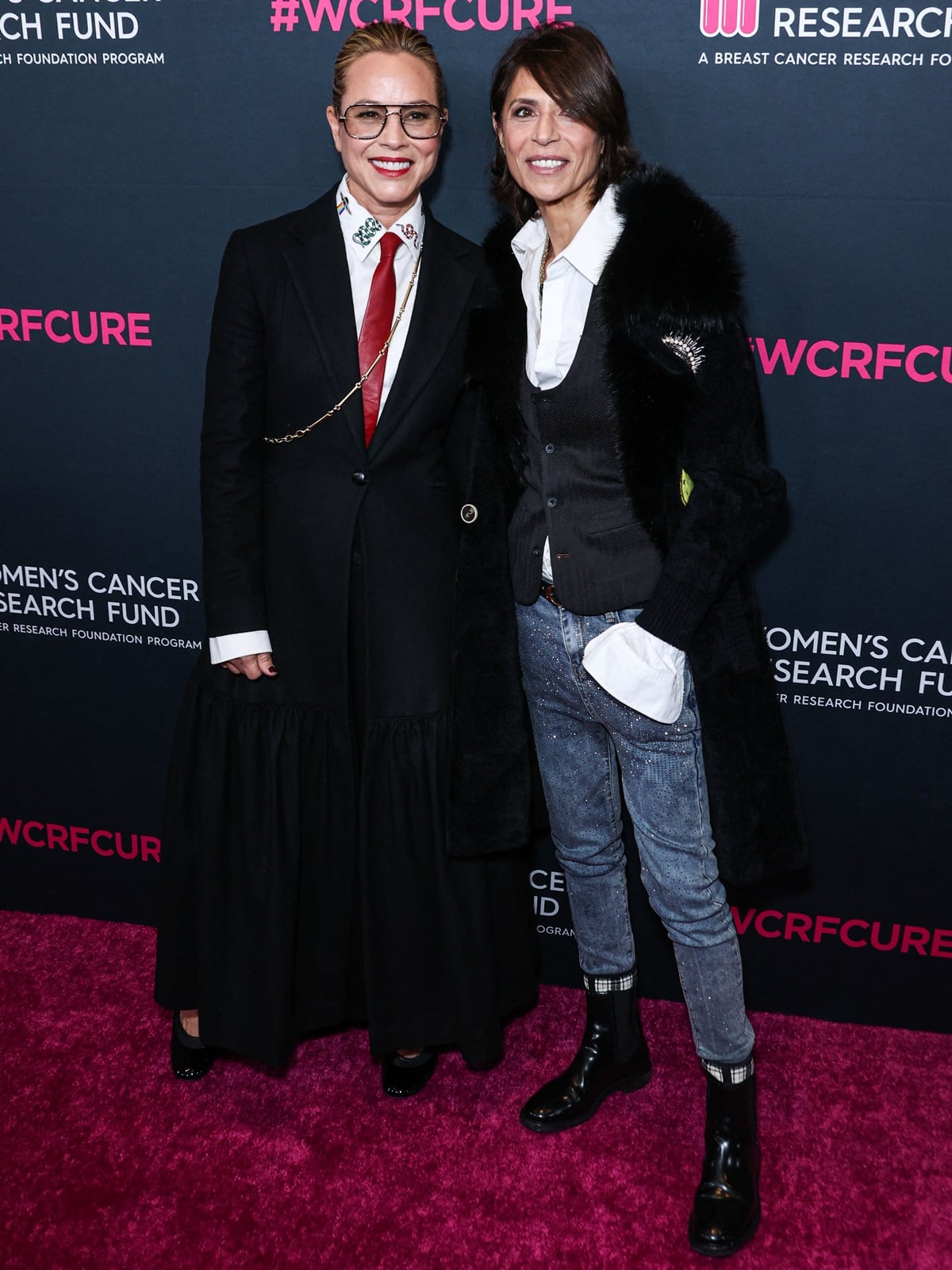 Maria Bello suited up in a sharp black blazer, white shirt, and red tie paired with a tiered maxi skirt and heels, while Dominique Crenn rocked glittery jeans, a statement coat, and glossy combat boots for an edgy-chic couple look