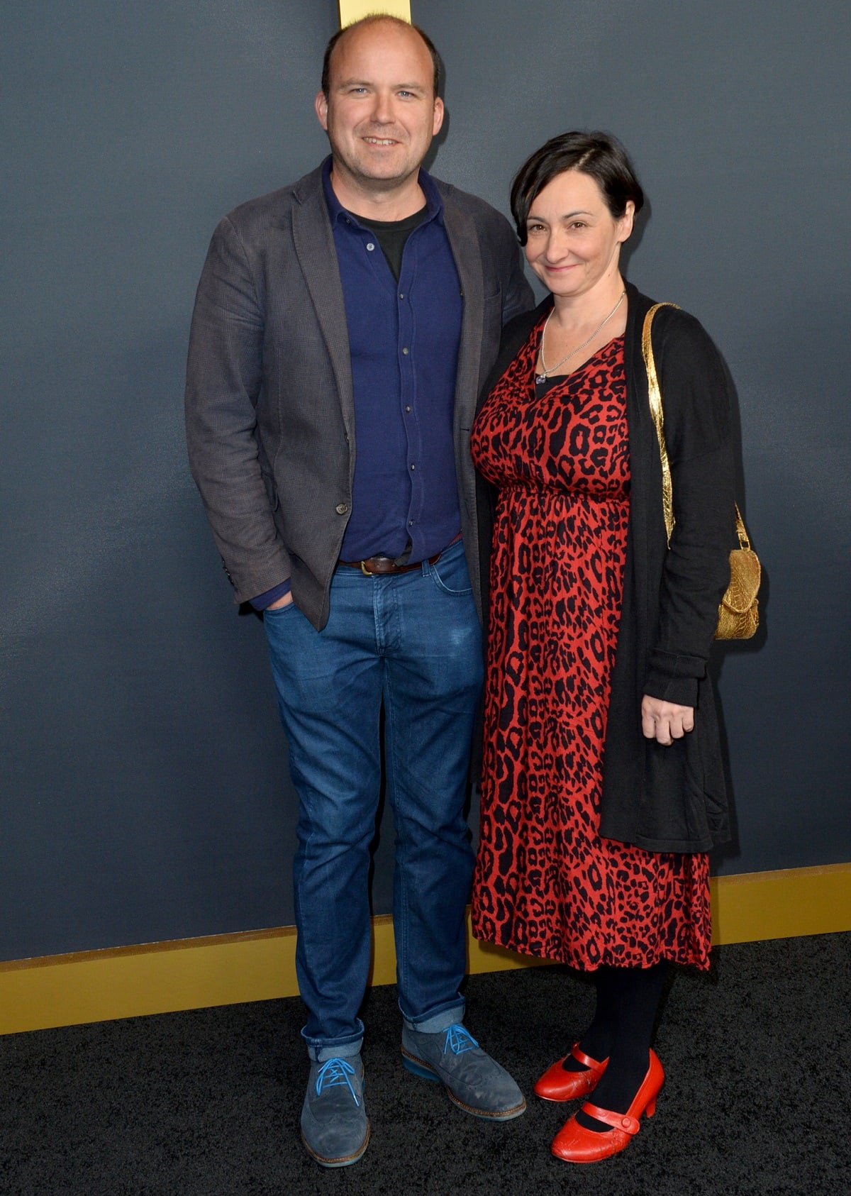 Posing with his wife, Pandora Colin, Rory Kinnear kept it casual in a navy button-down and blazer paired with denim jeans and slate gray suede shoes featuring bright blue laces, while Pandora stood out in a red leopard-print dress and bold red Mary Jane heels