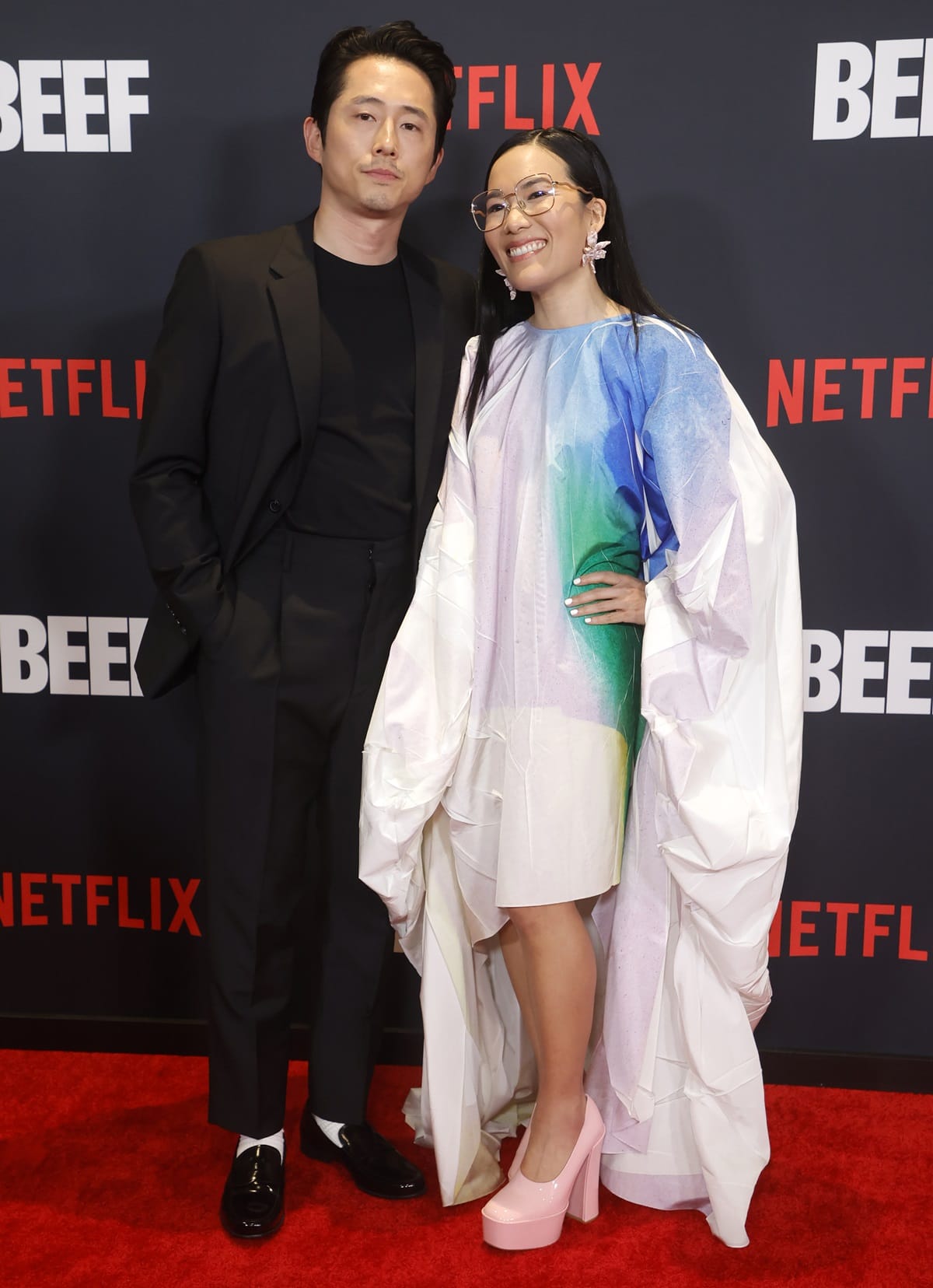 Despite Ali Wong’s towering pink platform heels, she still stood noticeably shorter than co-star Steven Yeun, whose sleek black suit and loafers offered a sharp contrast to her voluminous watercolor gown