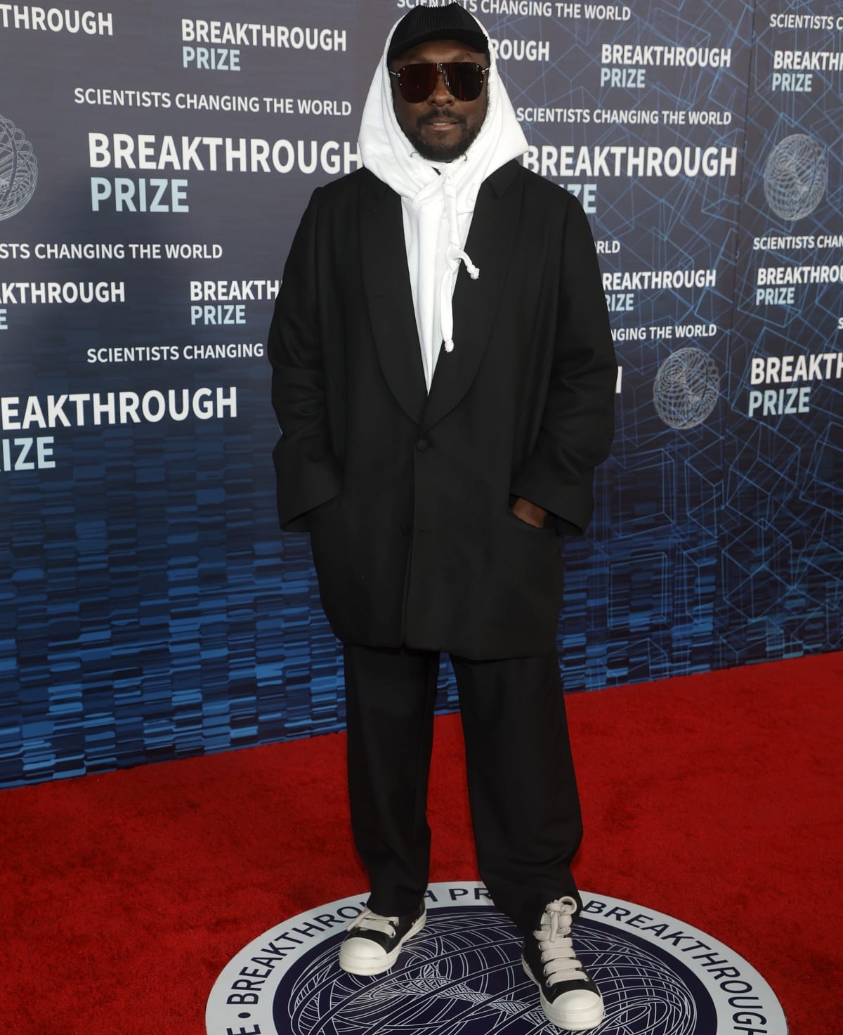 will.i.am keeps it cool and casual in a hoodie layered under a tailored oversized coat with matching sneakers at the 9th Annual Breakthrough Prize Ceremony