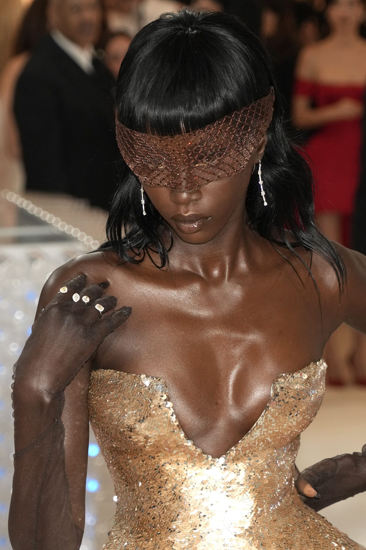 Anok Yai pairs her shimmering metallic dress with a Piers Atkinson embellished mask and sheer opera gloves