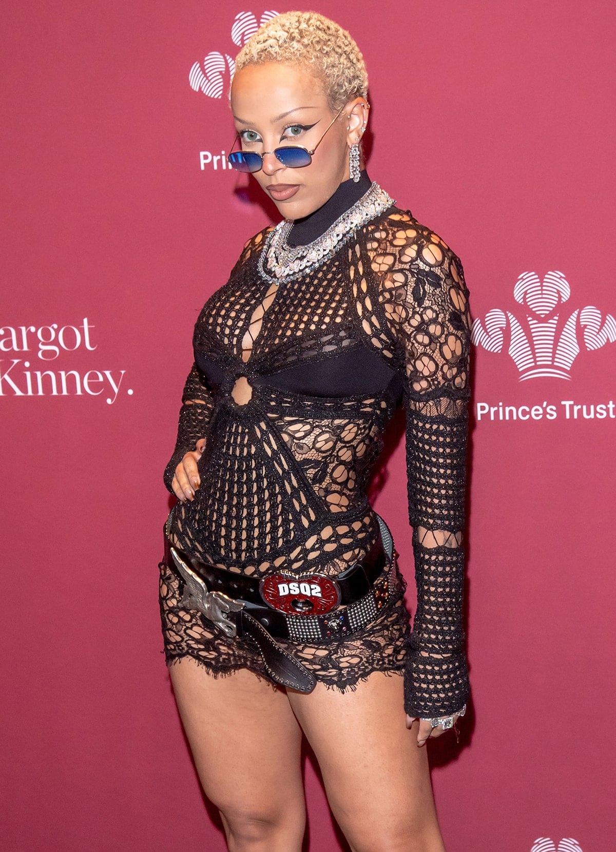 Doja Cat wears her buzzcut hair and dramatic winged eyeliner, accessorizing her Roberto Cavalli dress with a bold Dsquared2 belt