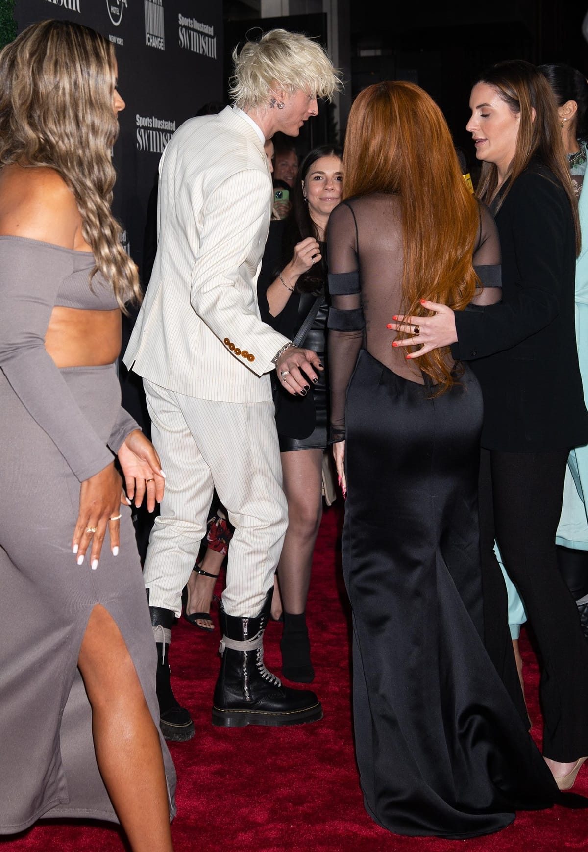 Machine Gun Kelly paired a sharply tailored white pinstripe Vivienne Westwood suit with towering, chunky black platform combat boots, creating a bold punk-meets-formal contrast that echoed Megan Fox’s dramatic, high-impact look