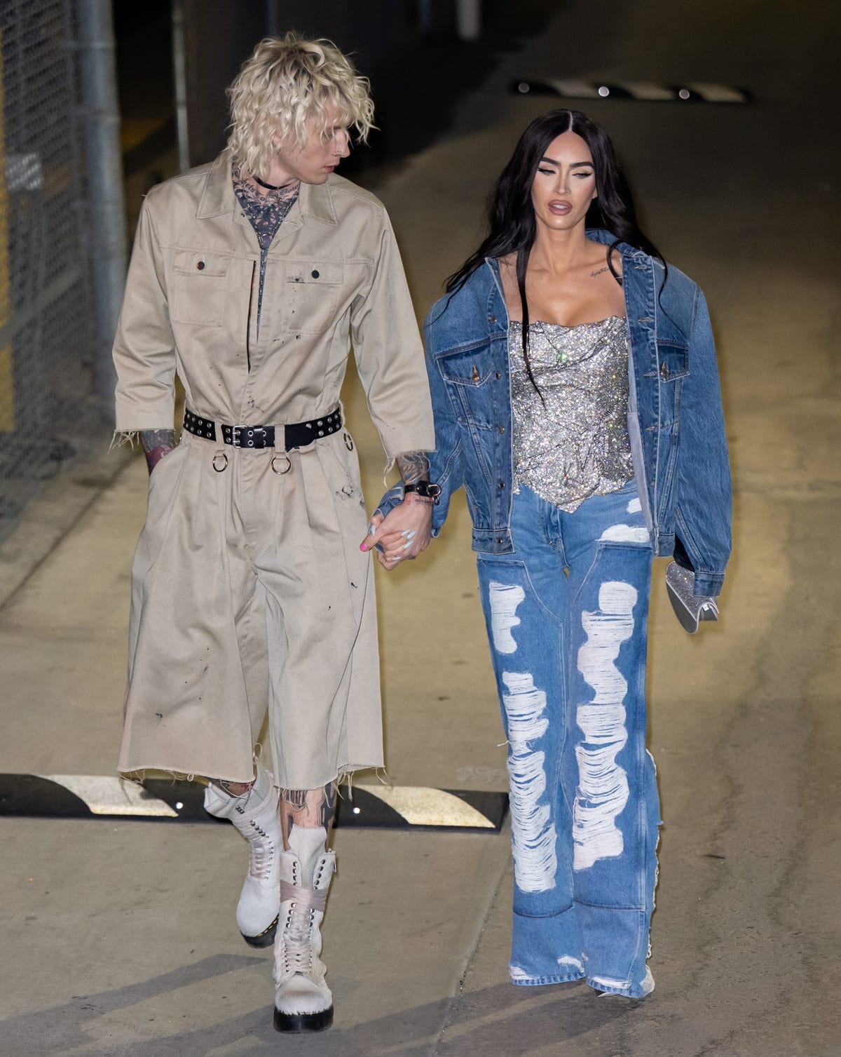 Megan Fox stepped out in support of Machine Gun Kelly outside Jimmy Kimmel Live! on December 7, 2022, pairing distressed wide-leg jeans and a shimmering silver corset with an oversized denim jacket, while MGK grounded the look in lace-up boots that added a utilitarian edge