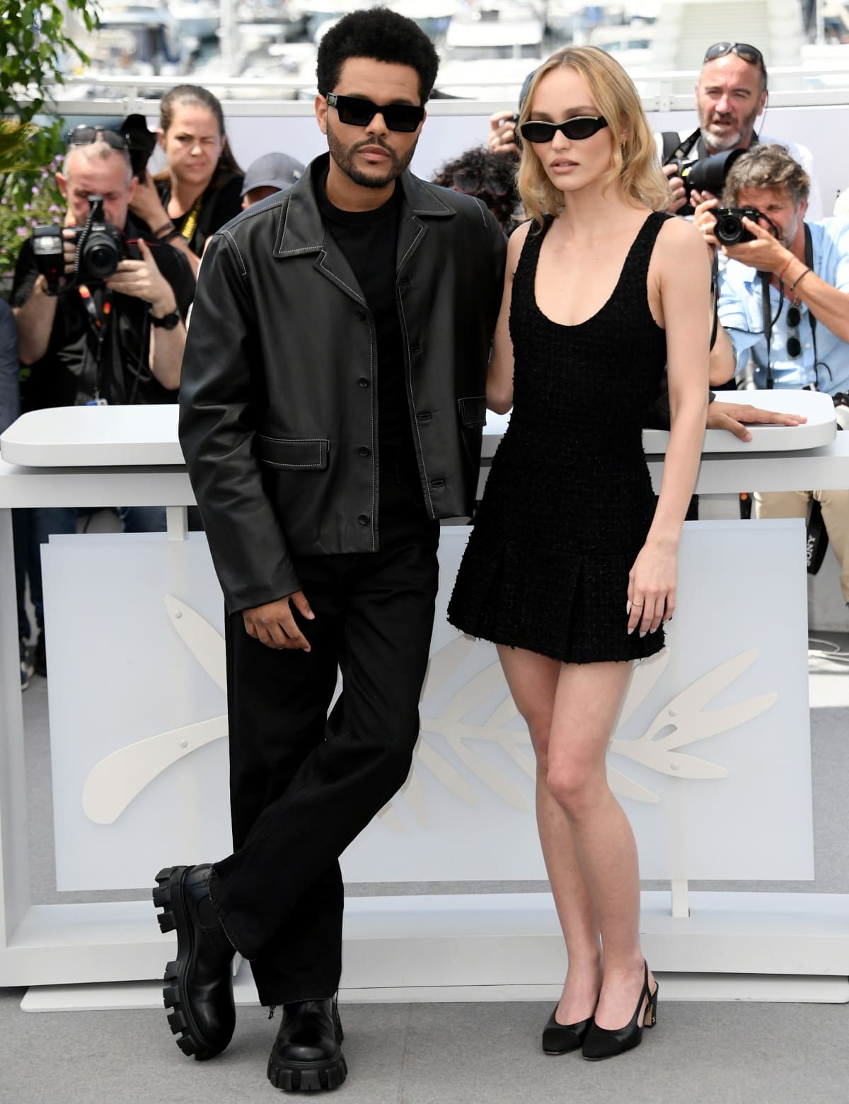At The Idol photocall during the 76th Cannes Film Festival on May 23, 2023, Abel Tesfaye paired chunky black leather boots with a sleek Loewe jacket, while Lily-Rose Depp balanced French-girl glamour in a black iridescent Chanel mini dress styled with classic slingback kitten heels