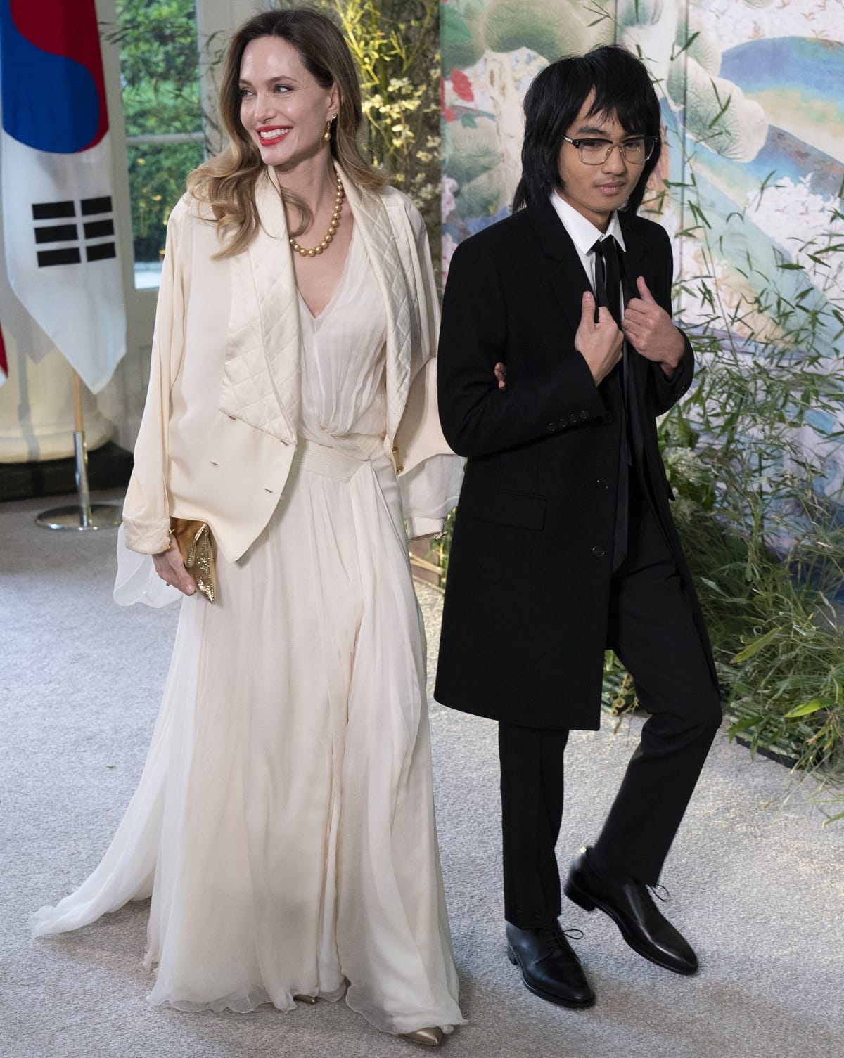 Angelina Jolie paired her ethereal ivory gown with metallic pointed-toe heels that peeked out elegantly beneath the flowing chiffon hem, while Maddox Jolie-Pitt completed his tailored black suit with polished lace-up dress shoes for a refined mother-son entrance