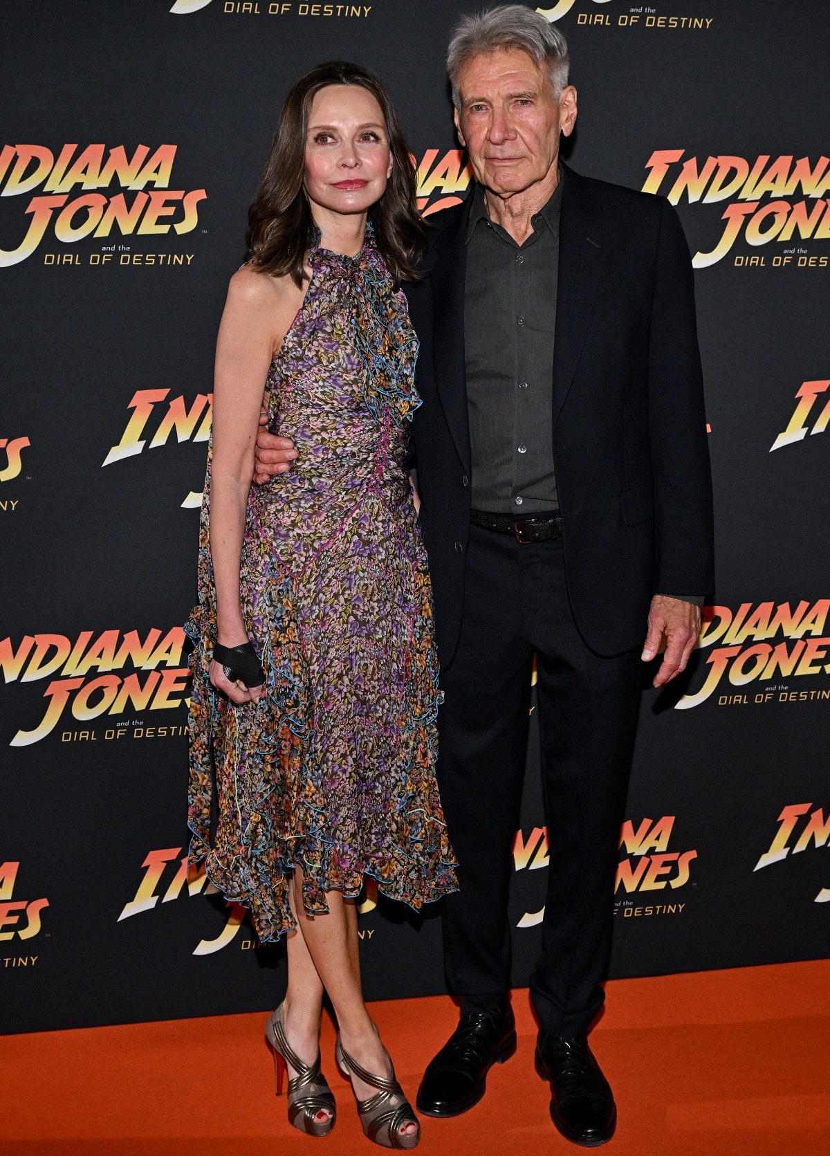 Calista Flockhart looked chic in a ruffled floral dress paired with metallic peep-toe platform heels, joining Harrison Ford—smart in a dark shirt and tailored suit—at the Indiana Jones and the Dial of Destiny party during the 76th Cannes Film Festival