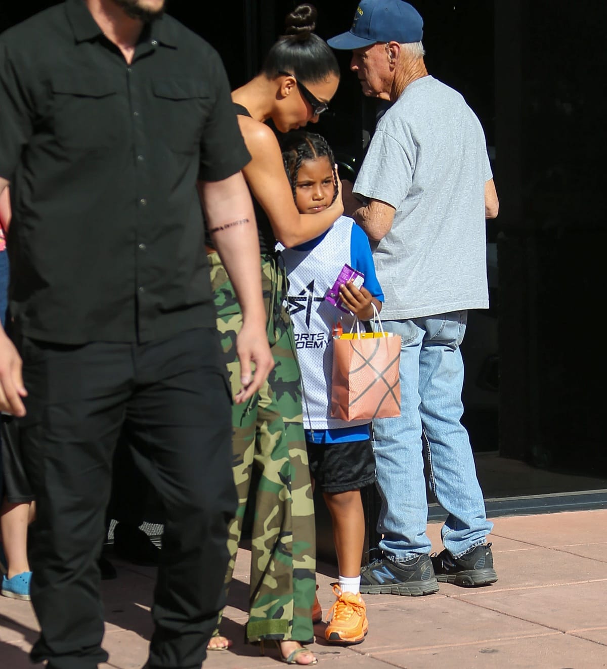 Kim Kardashian paired green open-toe heels with camo pants, while her son Saint West stood out in bright orange Nike sneakers