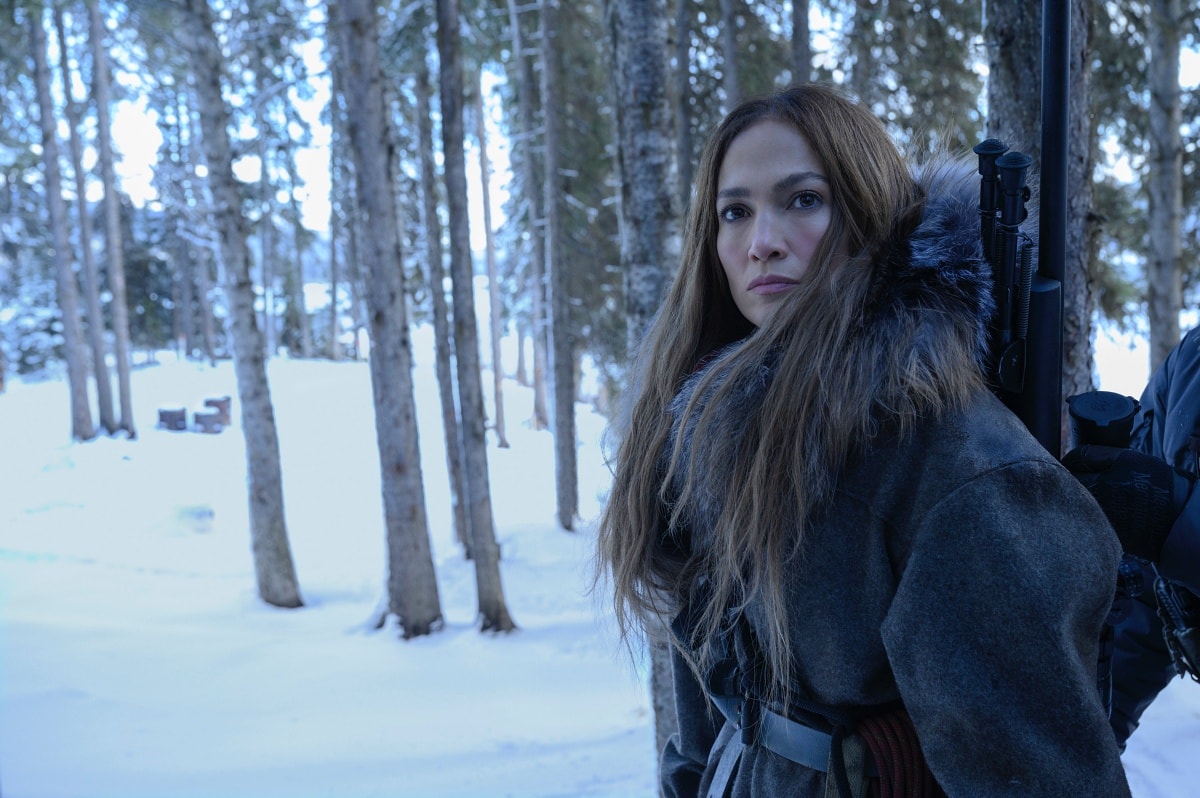 In a gripping winter scene, Jennifer Lopez’s character braces against the cold, clad in a fur-trimmed parka as she prepares for survival in The Mother