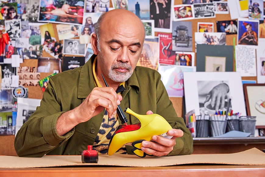 Christian Louboutin meticulously hand-paints the iconic red sole on a yellow heel, showcasing the artistry and dedication behind each luxury shoe
