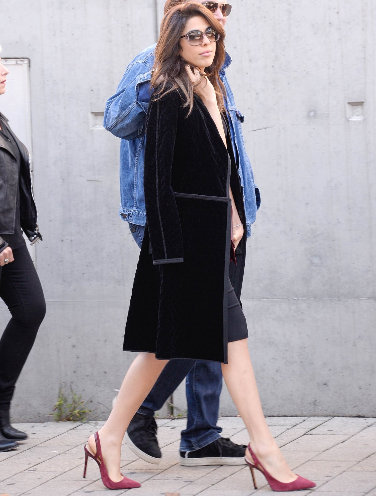 Daniela Pick attending the unveiling of Catherine Deneuve’s honoring plate at the 8th Festival Lumière in Lyon, France on October 15, 2016, wearing a sleek black velvet coat layered over a black dress and pairing the look with burgundy pointed-toe slingback stiletto heels and oversized sunglasses