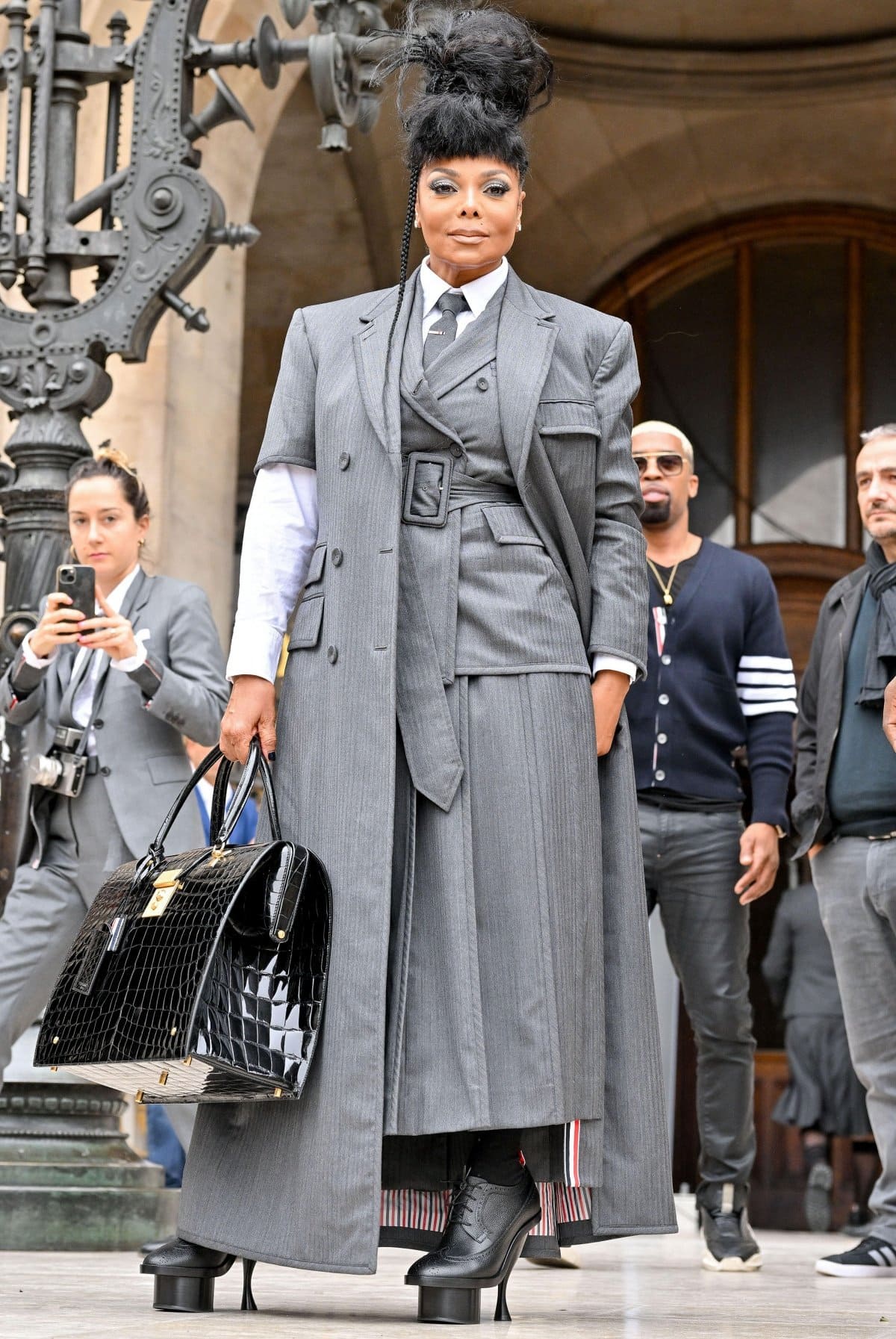 Pop icon Janet Jackson turned heads in towering platform lace-up heels and a sharply tailored layered grey suit while attending the Thom Browne Womenswear Spring/Summer 2023 show