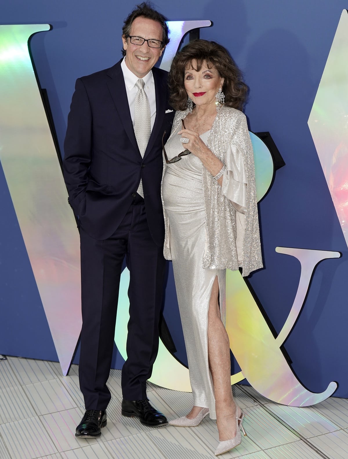 Percy Gibson and Dame Joan Collins posing together for photos at the VA Summer Party and DIVA Exhibition Preview
