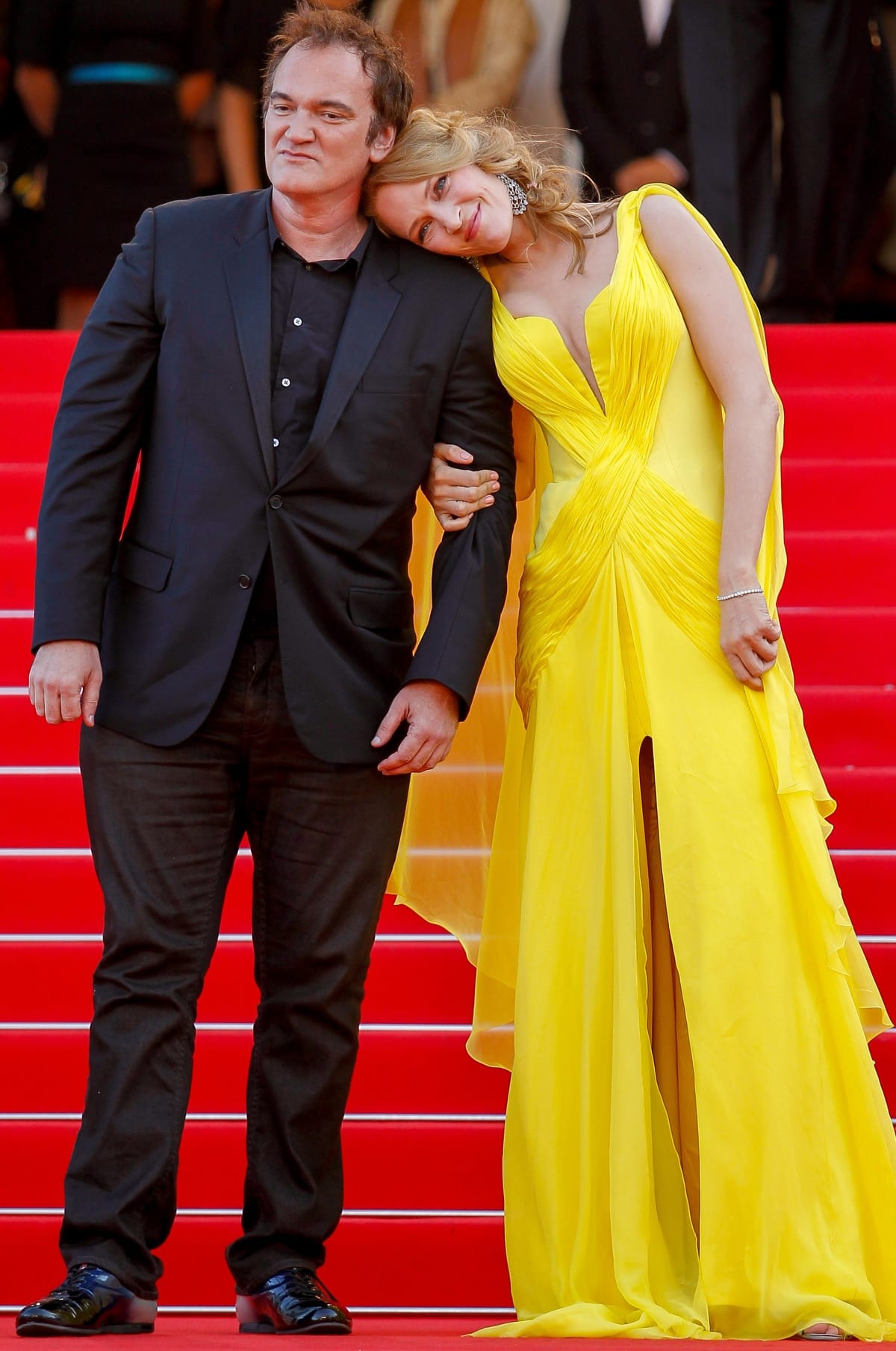 Uma Thurman lit up the red carpet at the Sils Maria premiere during the 67th Cannes Film Festival on May 23, 2014, stunning in a canary yellow Atelier Versace gown with a flowing train, paired with Chopard jewels, metallic heels, and a soft braided updo as she posed alongside Quentin Tarantino