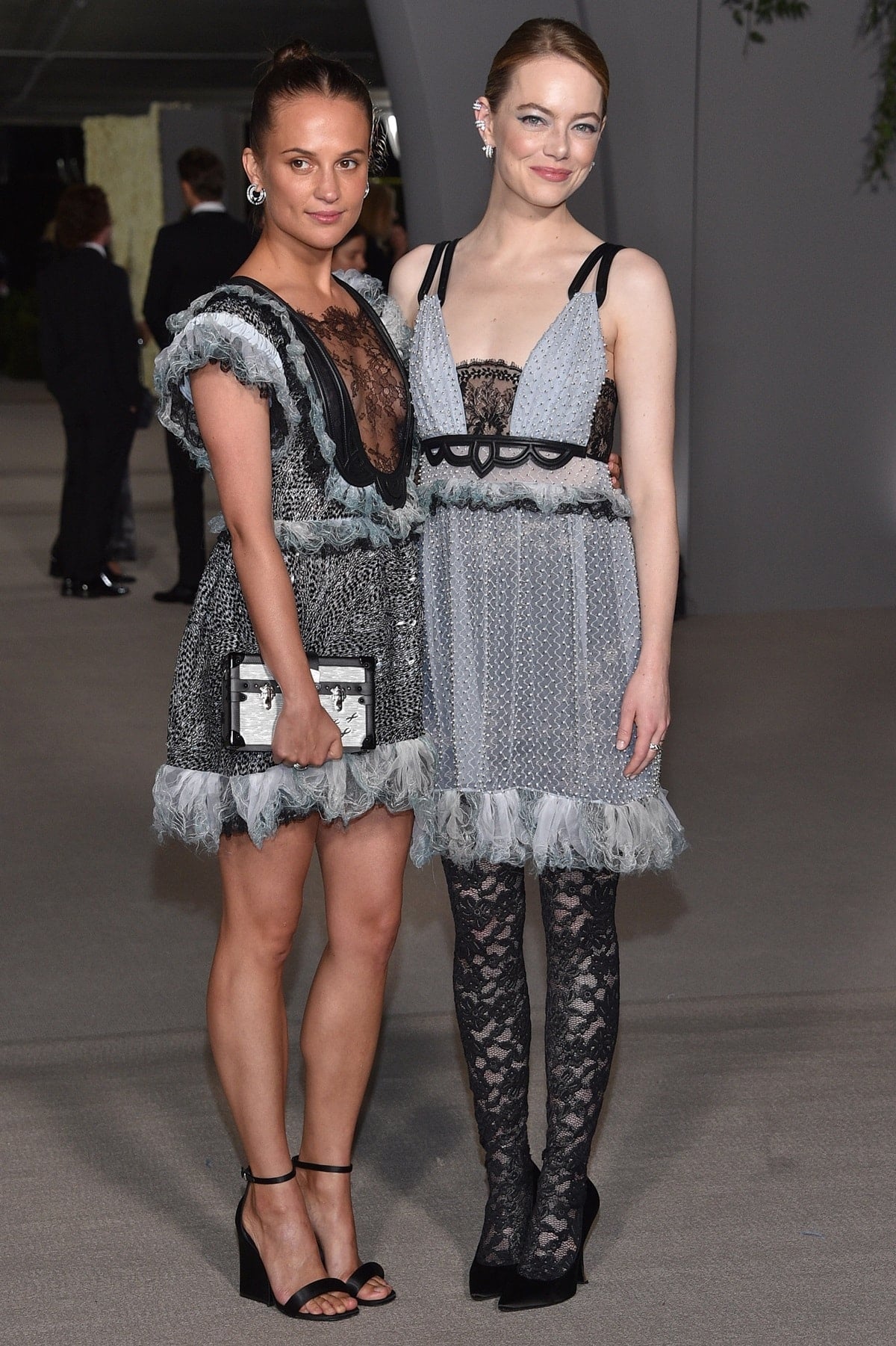 At the 2022 Academy Museum Gala, Louis Vuitton ambassadors Alicia Vikander and Emma Stone arrived in coordinated gray-and-black lace looks from the brand’s Spring 2023 collection, pairing their contrasting dresses with sleek black heels