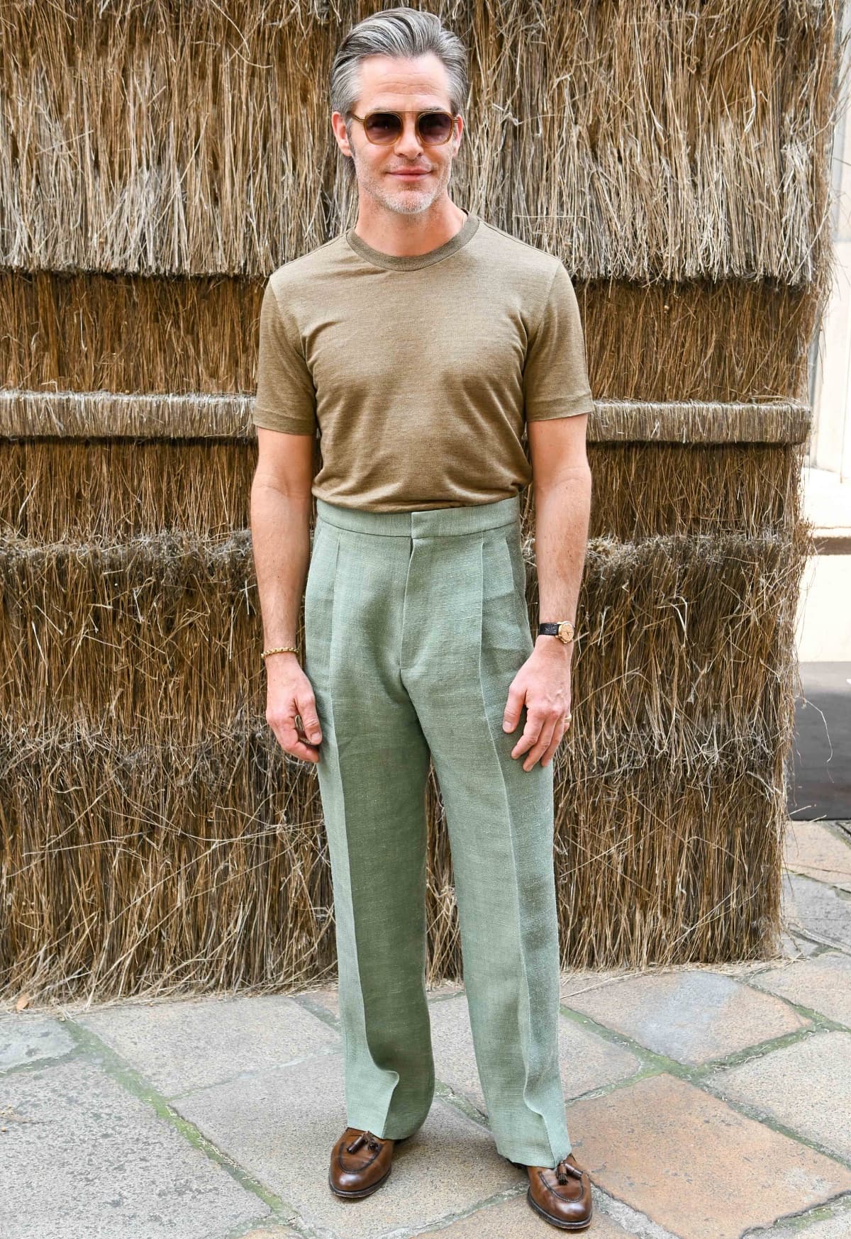 Chris Pine looked effortlessly stylish at the Zegna Menswear Spring/Summer 2024 show, pairing a light brown knit tee with sage green pleated trousers and brown tasseled loafers for a refined, relaxed look