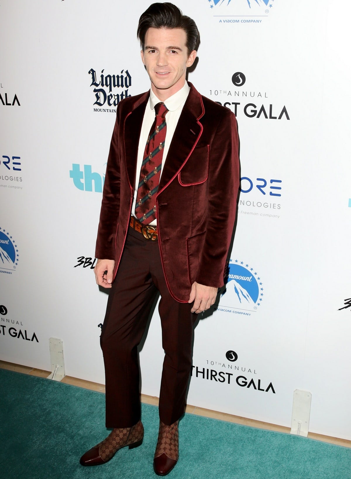 Drake Bell showcased retro flair at the Thirst Project’s 10th Annual Thirst Gala in Los Angeles, wearing a burgundy velvet suit with contrast piping, a patterned tie, and Gucci monogram ankle boots