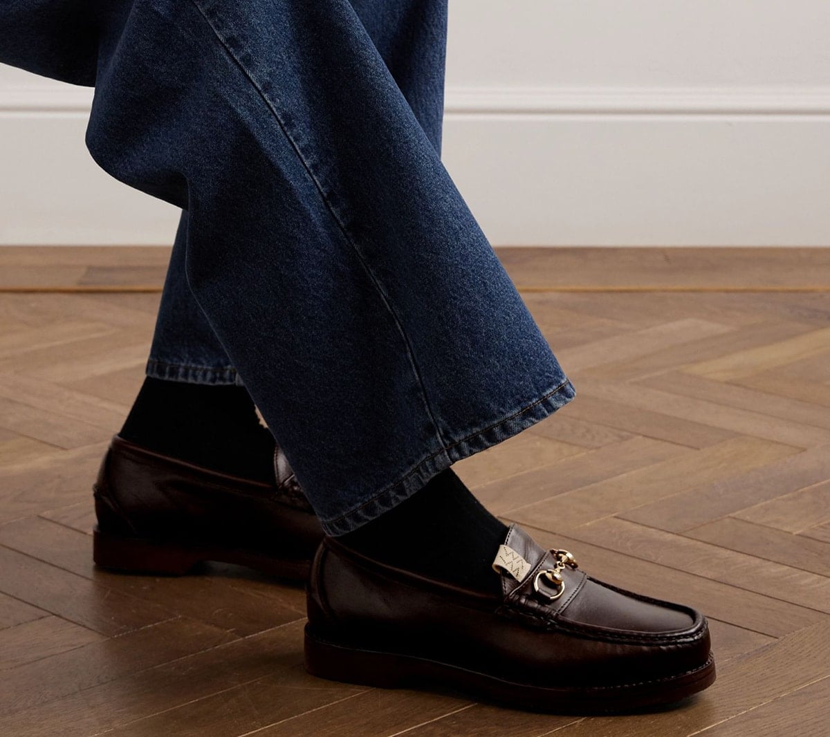 Dark brown leather horsebit loafers add a refined finish to relaxed straight-leg jeans, illustrating how traditional dress shoes can work with casual menswear