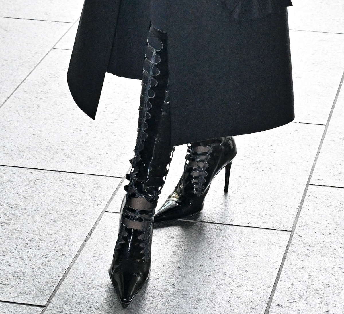 A closer look at Lisa Rinna’s edgy knee-high patent leather lace-up boots, featuring pointed toes and stiletto heels for a striking Paris Fashion Week statement