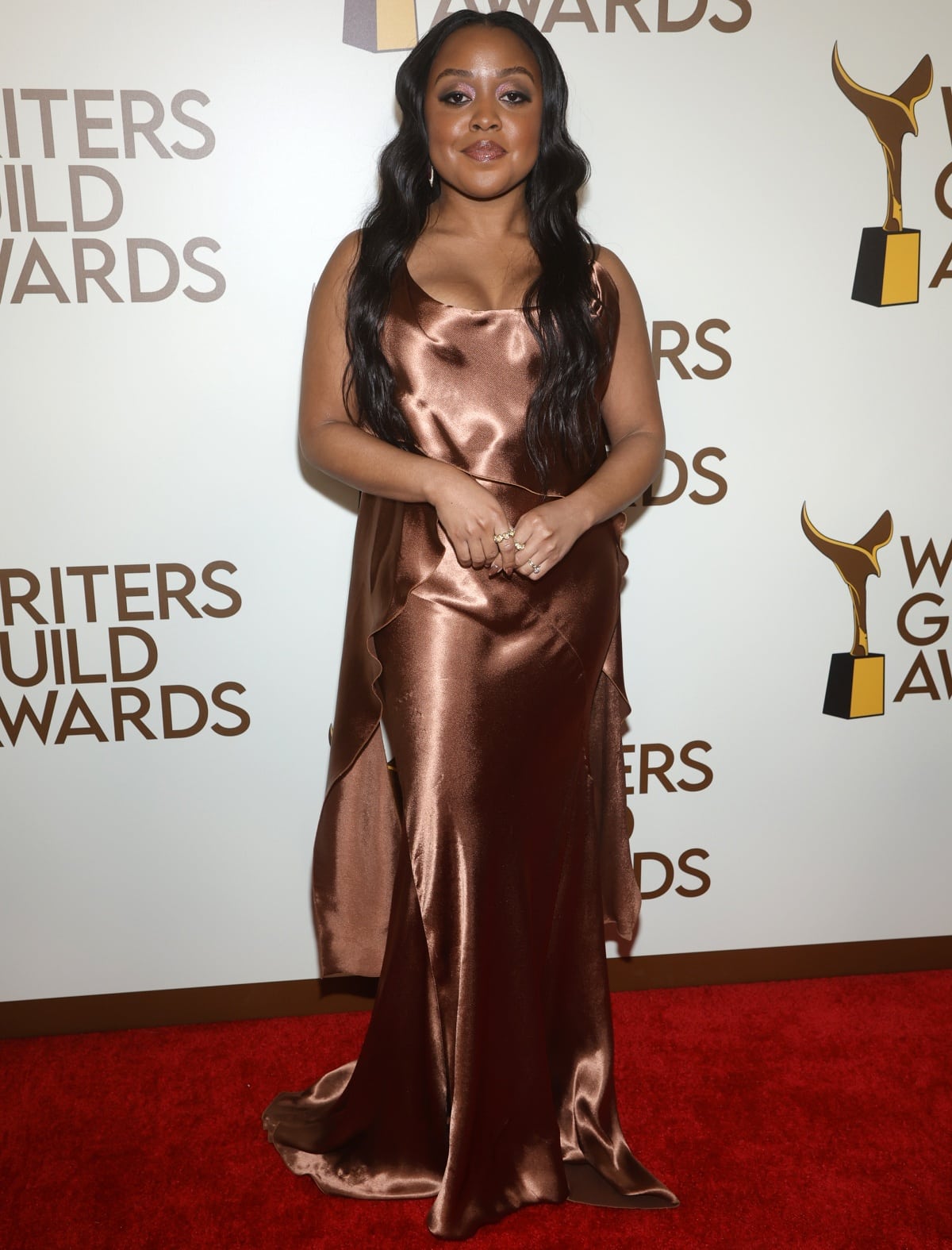 Quinta Brunson glowed in a silky bronze satin slip gown with cascading sleeves, letting the floor-length design elegantly graze the red carpet at the Writers Guild Awards