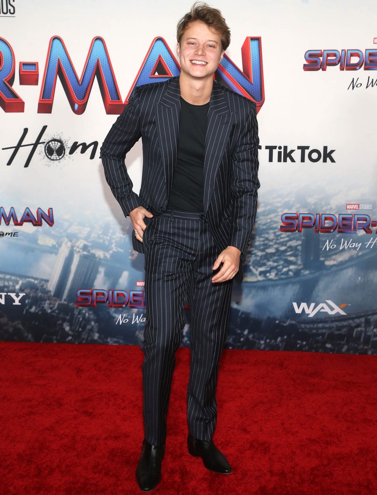 Rudy Pankow keeps it sharp and modern in a navy pinstripe suit paired with sleek black leather Chelsea boots at the Spider-Man: No Way Home premiere