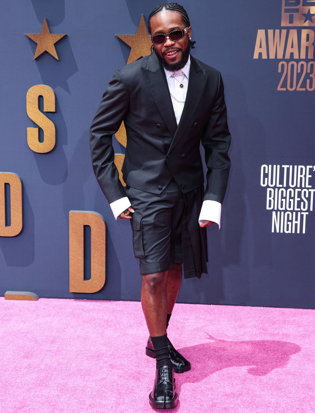 Shameik Moore brings avant-garde polish to the 2023 BET Awards in a Grayscale double-breasted jacket with extended cuffs and a pleated short-skirt hybrid, finished with Versace pearls and black Maison Margiela Tabi boots