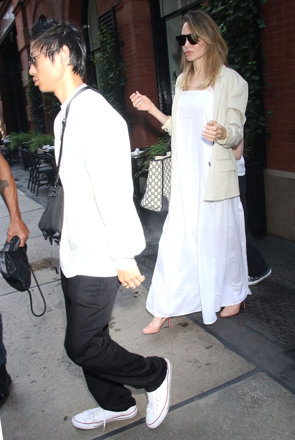 Angelina Jolie leans into effortless summer dressing in a breezy white maxi dress styled with nude Christian Louboutin pumps while out with Pax and Vivienne in New York City on August 18, 2023