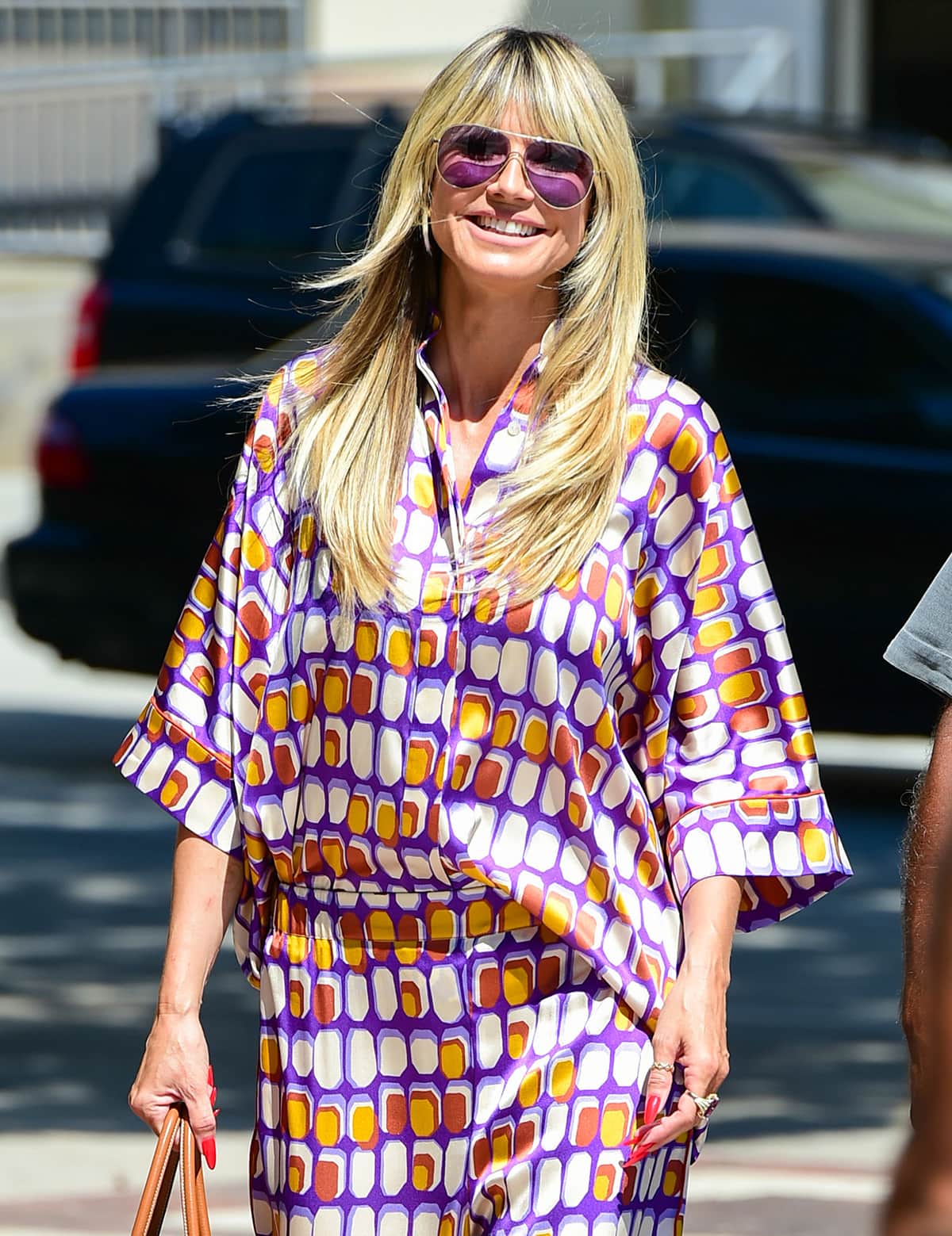 Heidi Klum keeps her look cohesive by wearing purple aviators and carrying a tan Hermès Birkin bag