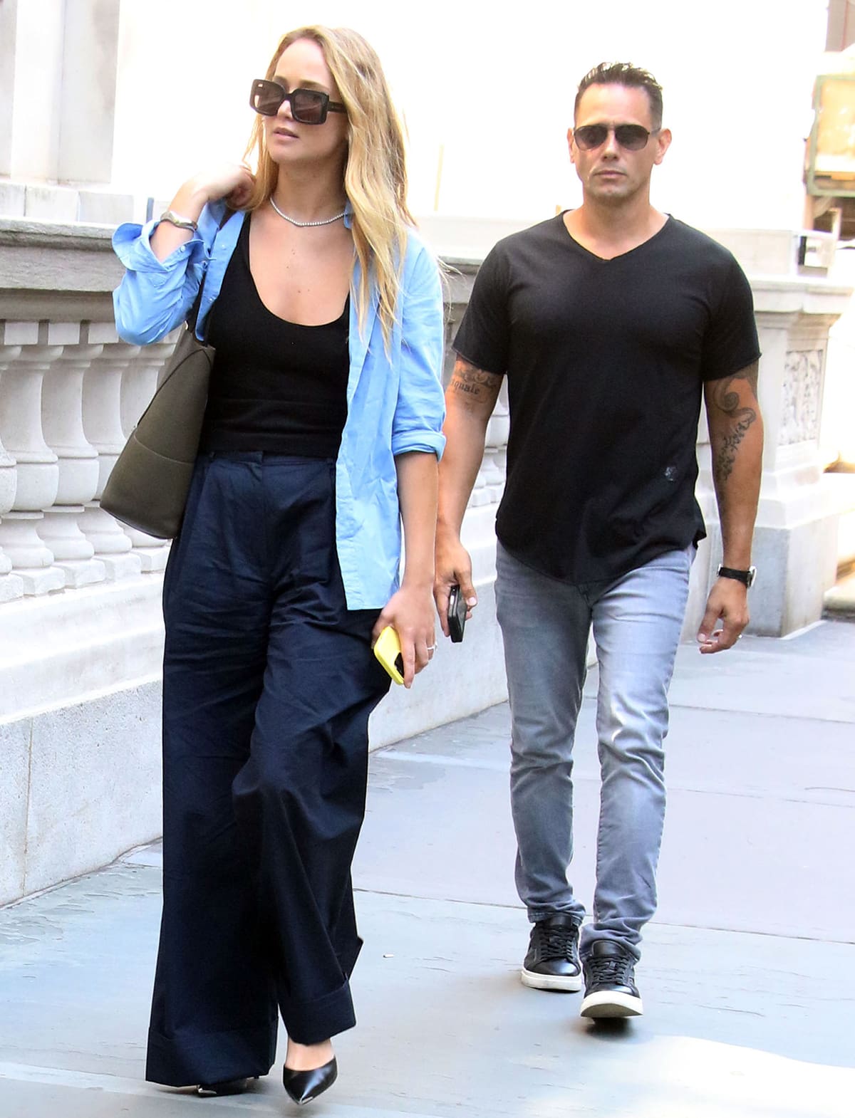 Jennifer Lawrence layers her black and navy outfit underneath a light blue shirt and finishes the look with black Celine pumps