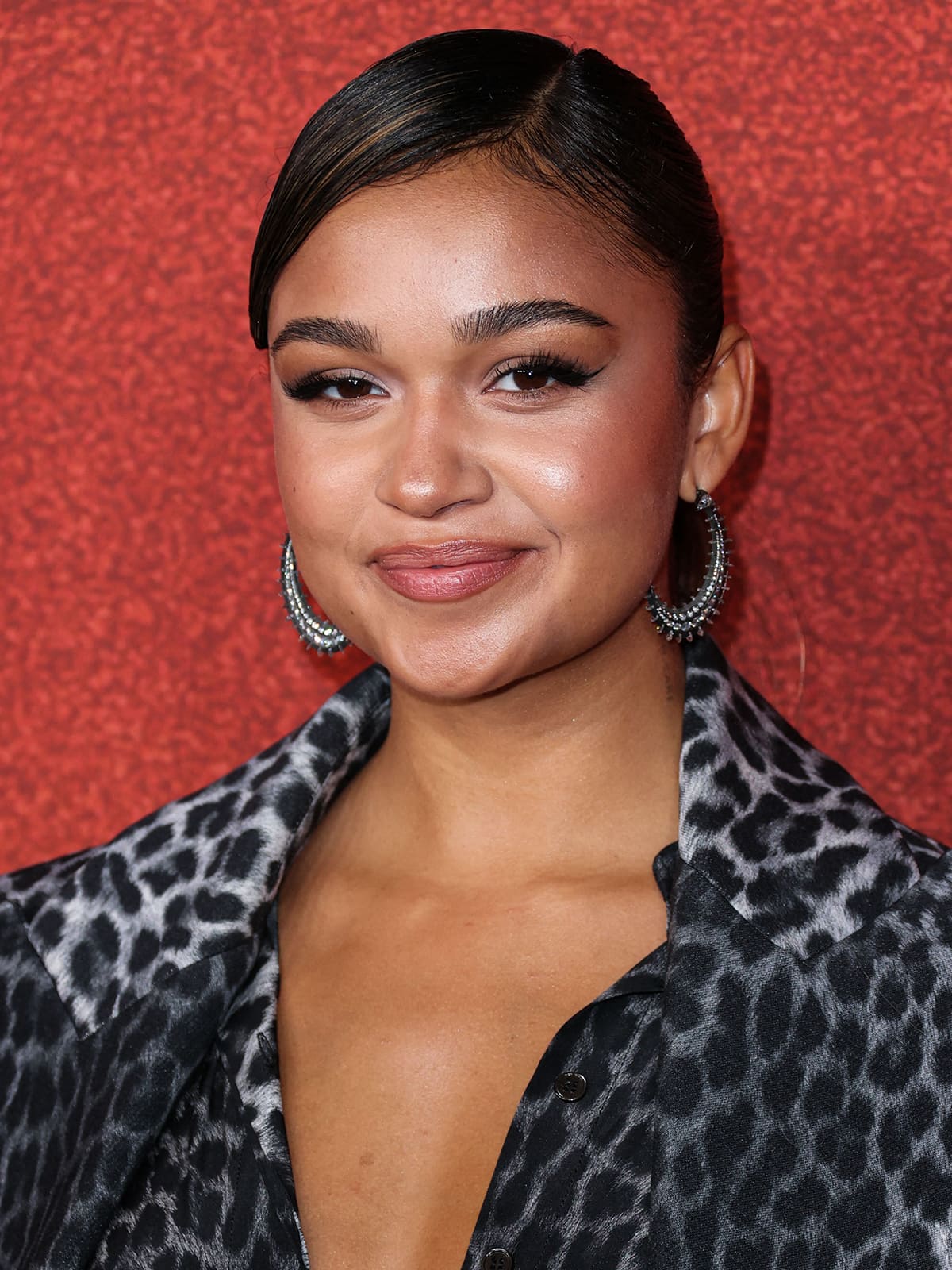 Madison Bailey wears a sleek ponytail and a bronzed glow with feathery eyelashes and nude pink lipstick