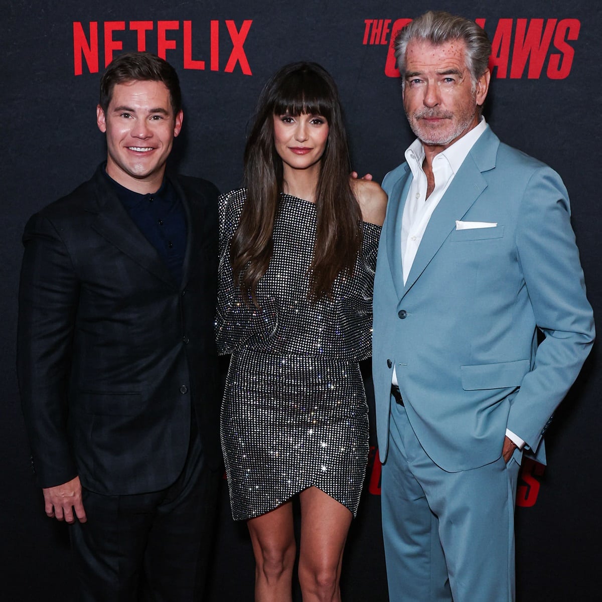 Nina Dobrev shines in a sparkling mini dress as she poses with her The Out-Laws co-stars Adam Devine and Pierce Brosnan at the Netflix premiere