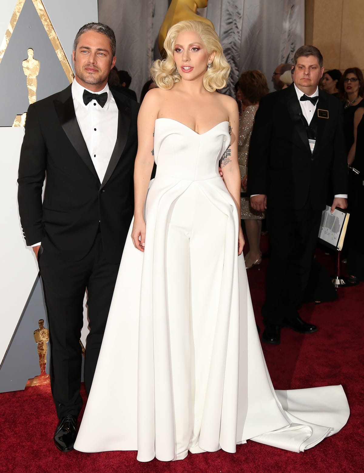 Despite Taylor Kinney being over 9 inches taller than Lady Gaga, her hidden high heels under the flowing dress make her appear nearly his height on the red carpet
