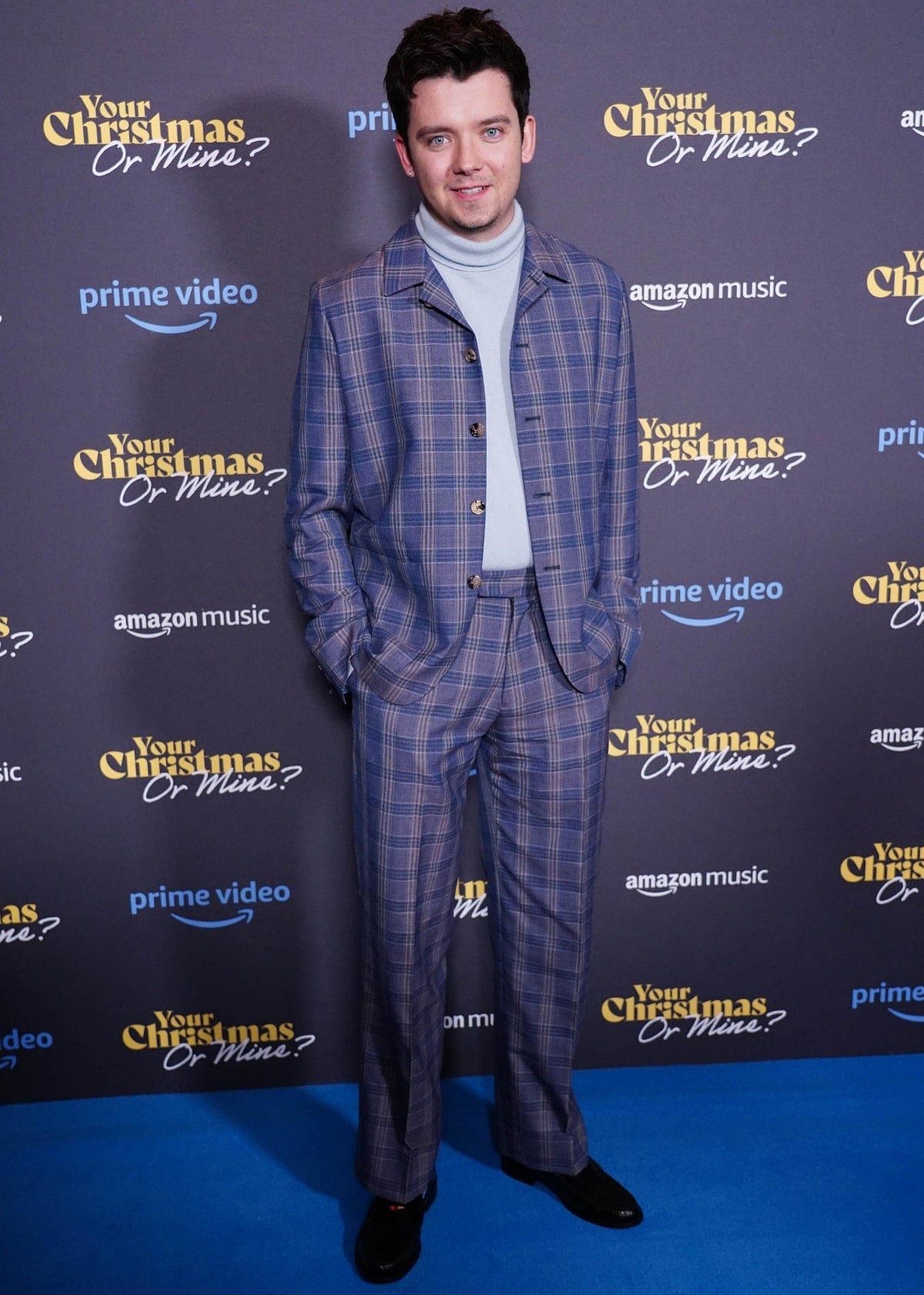 Asa Butterfield stepped out in a retro-inspired blue plaid suit paired with a powder blue turtleneck and classic black velvet loafers at the premiere of Your Christmas or Mine?, blending vintage charm with modern polish