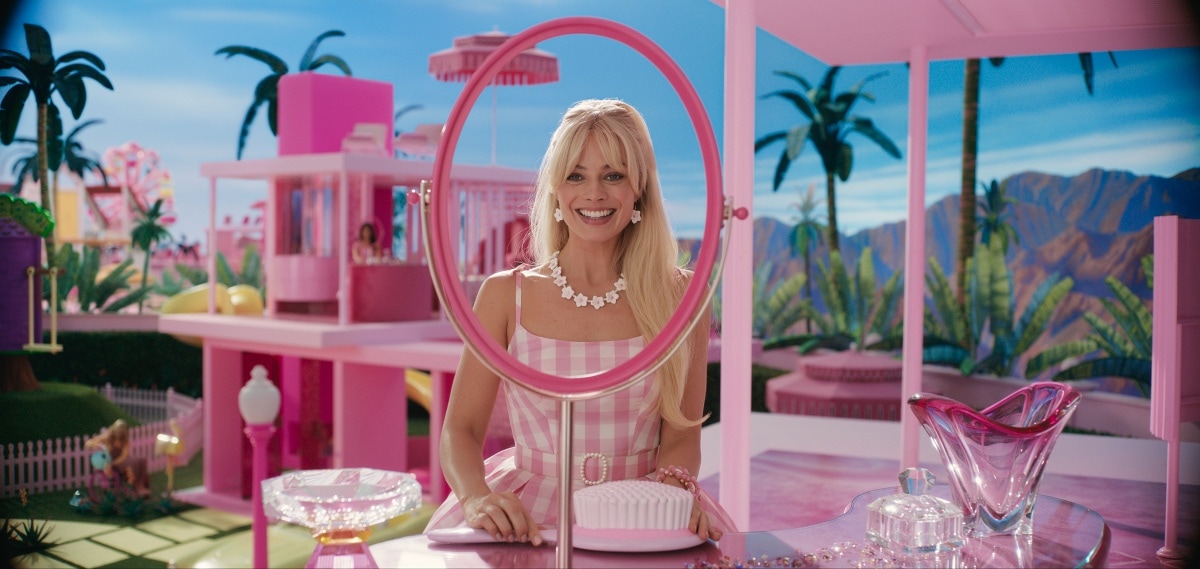 Margot Robbie brings the iconic doll to life as Barbie in Greta Gerwig’s 2023 fantasy comedy Barbie, dazzling in a pastel pink gingham dress and matching accessories inside her dreamhouse