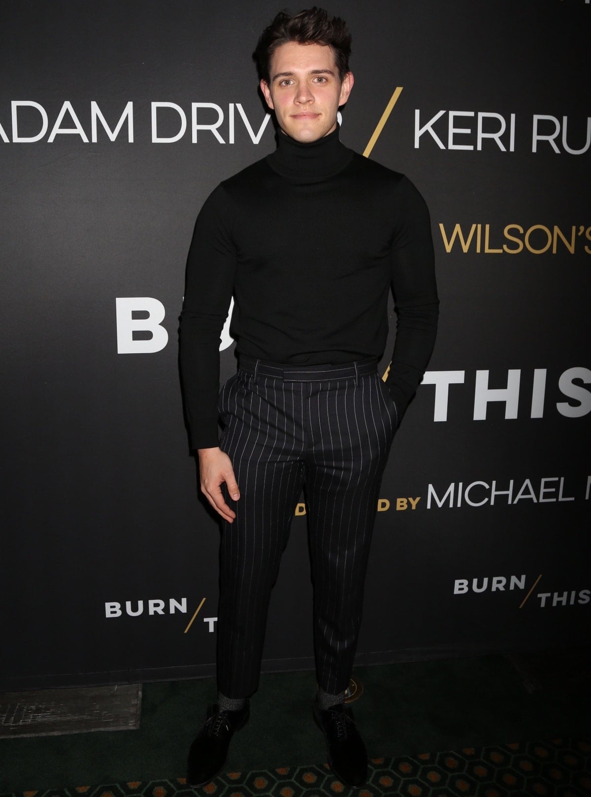 Casey Cott keeps it sleek and sophisticated in a black turtleneck paired with tailored pinstripe trousers, showcasing timeless style at a Broadway event