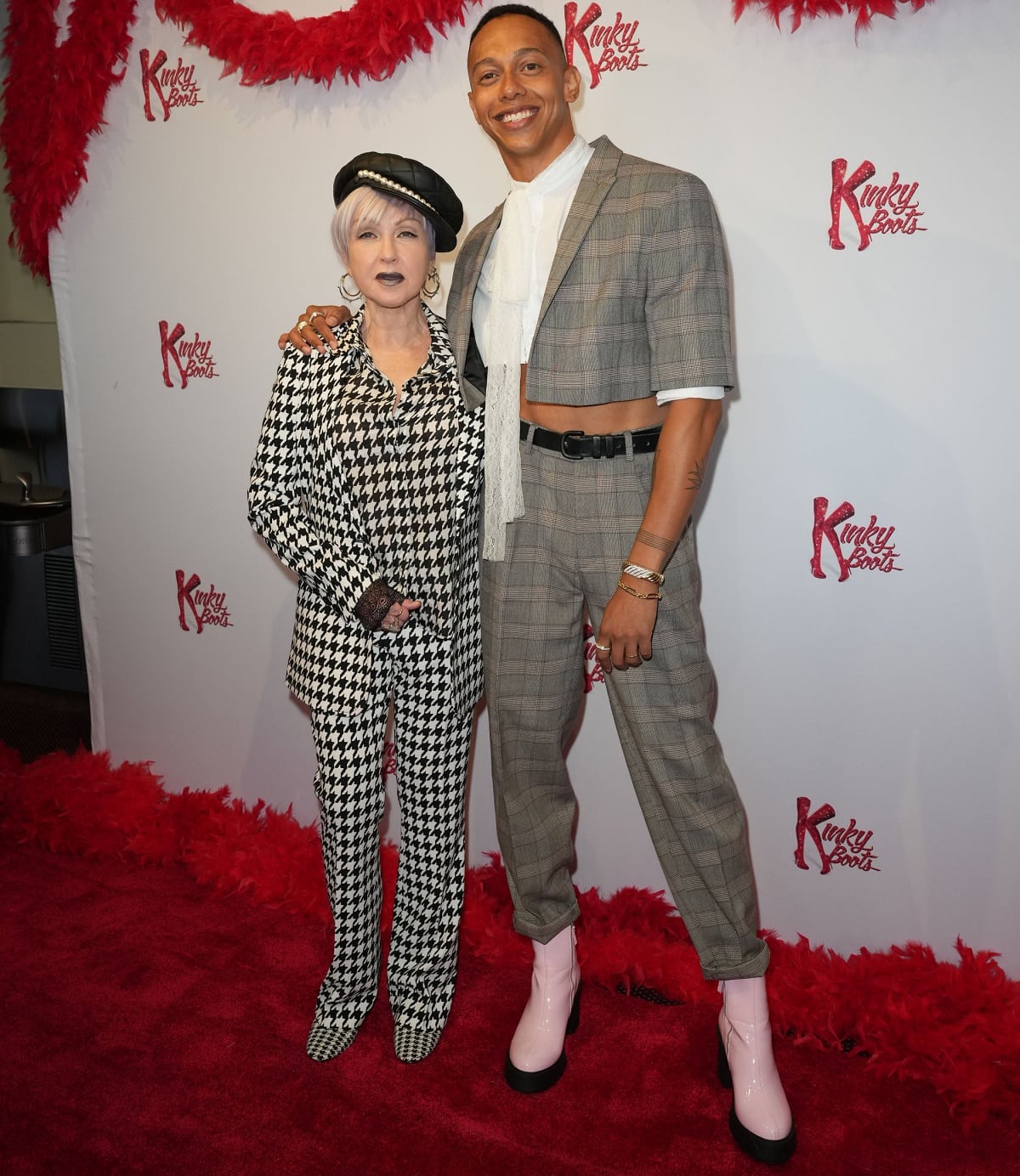Cyndi Lauper and Callum Francis both make a statement at the Kinky Boots event, with Lauper’s bold black-and-white houndstooth suit paired with black ankle boots and Francis rocking a modern plaid ensemble with striking pink platform boots